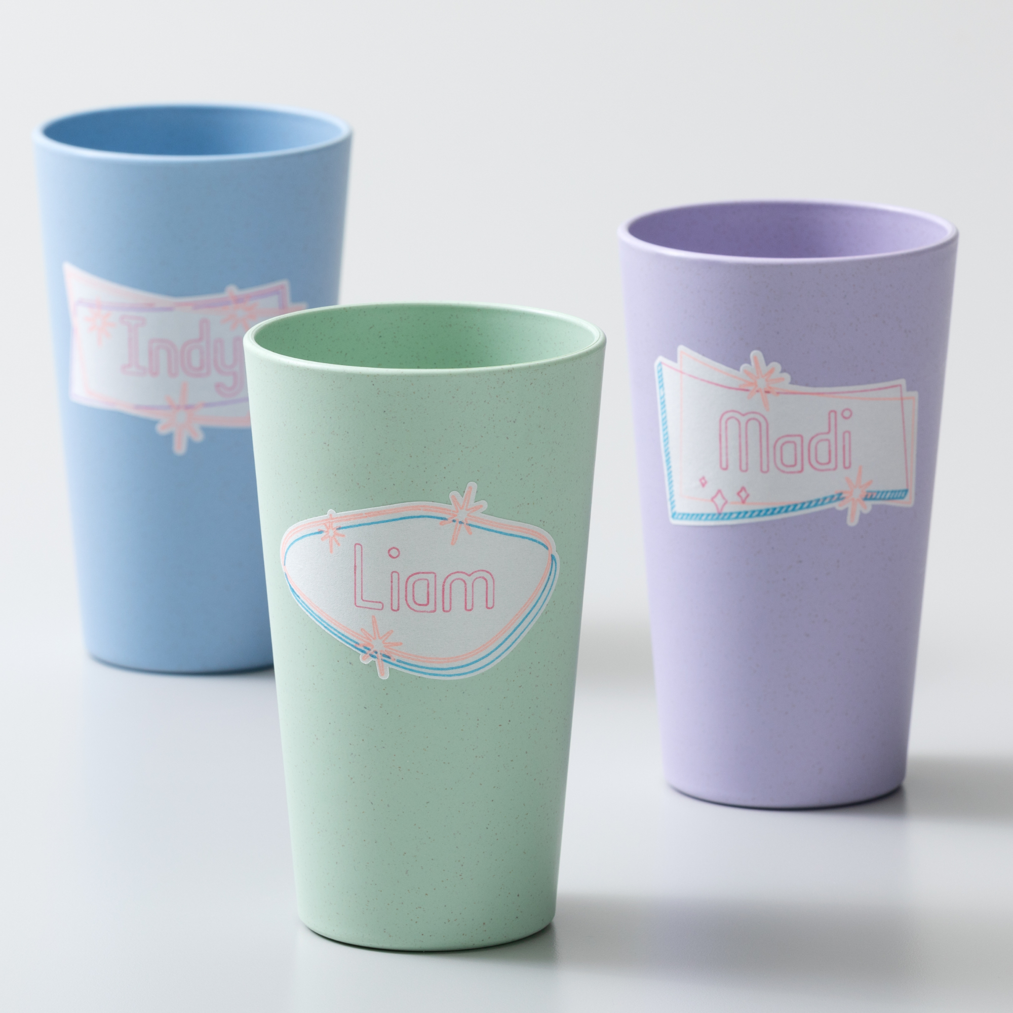 Drei bunte Becher mit Namen darauf.