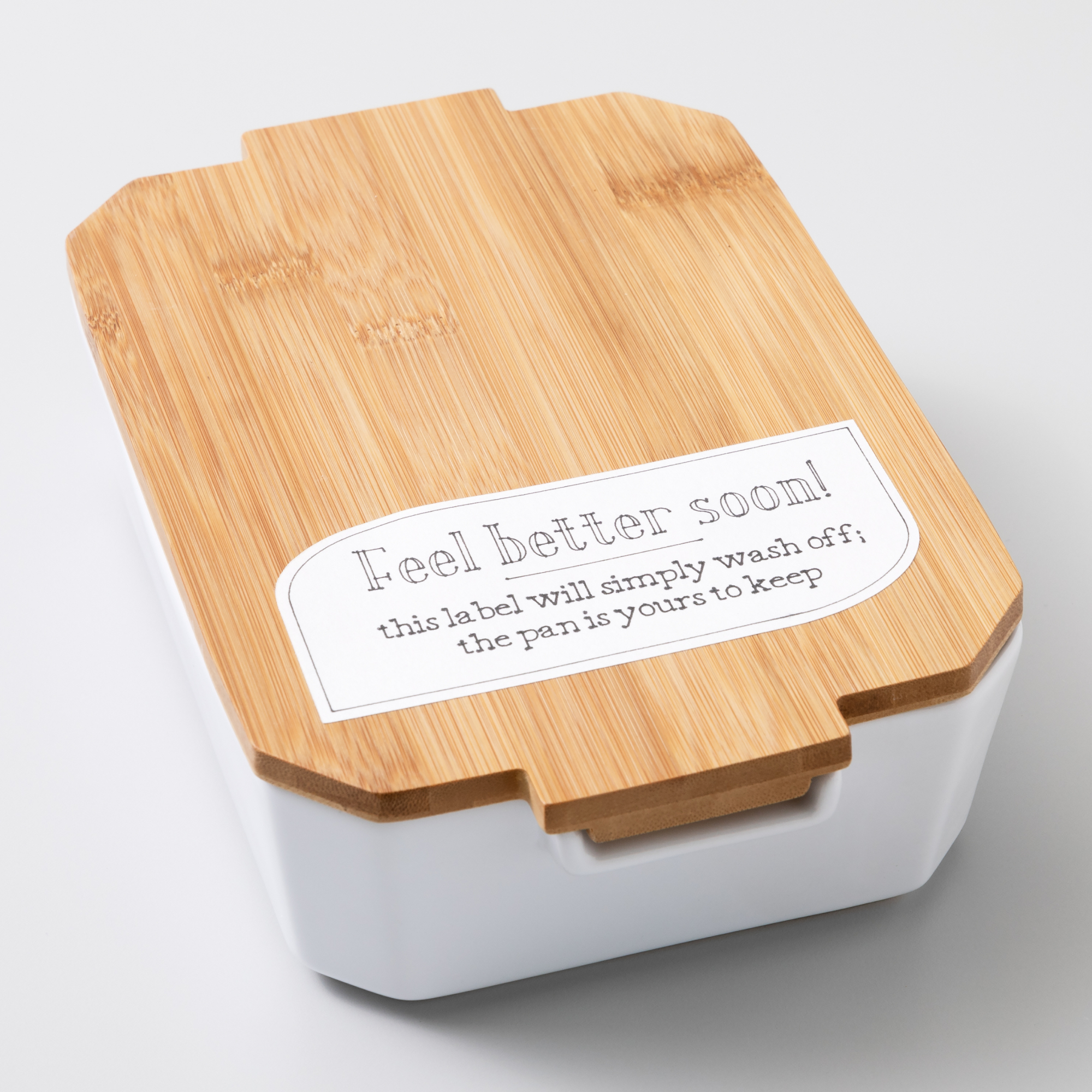 Weiße und Bambus-Lunchbox mit 'Gute Besserung!' Aufkleber oben.