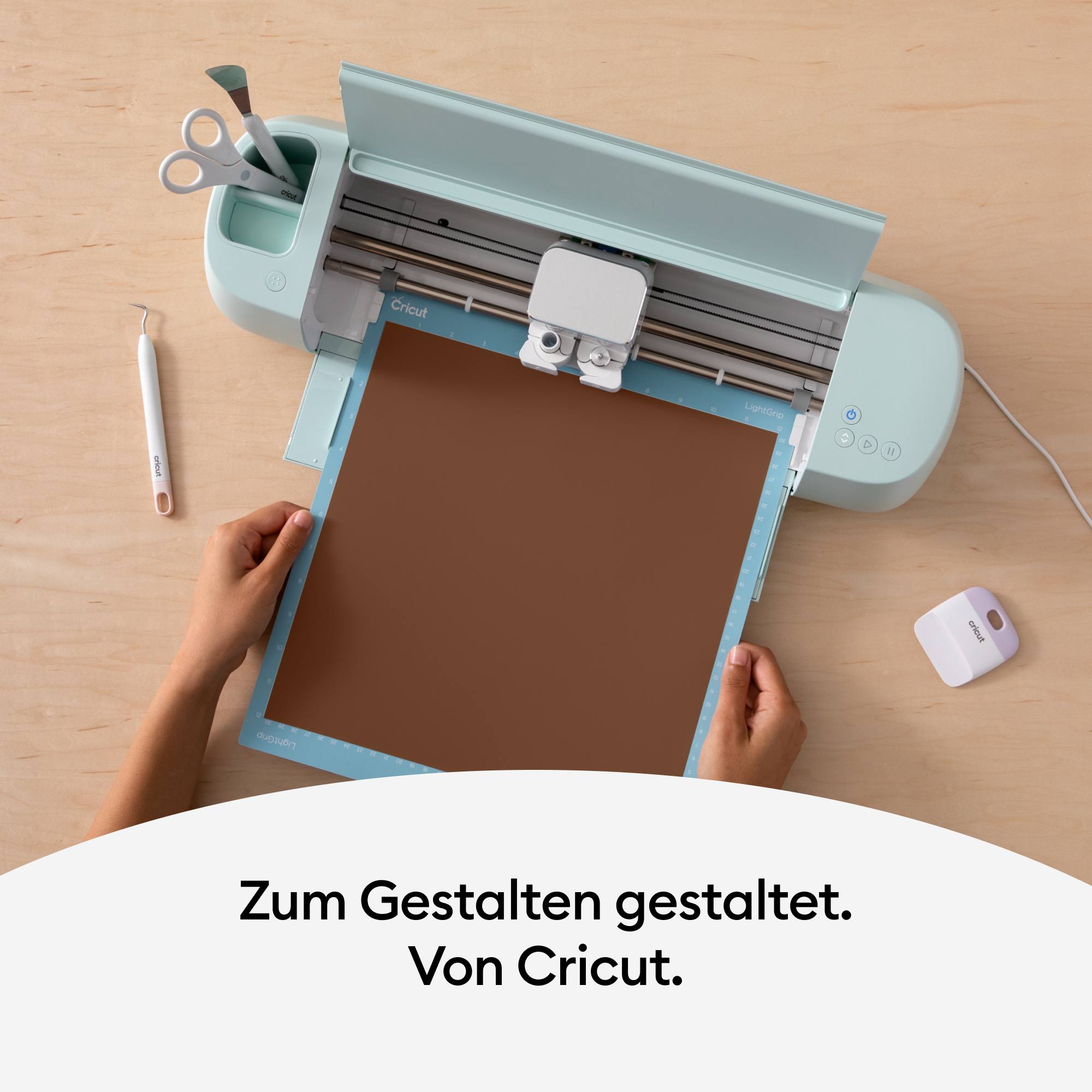 Eine Cricut-Maschine mit einem braunen Materialbogen, der geschnitten wird.