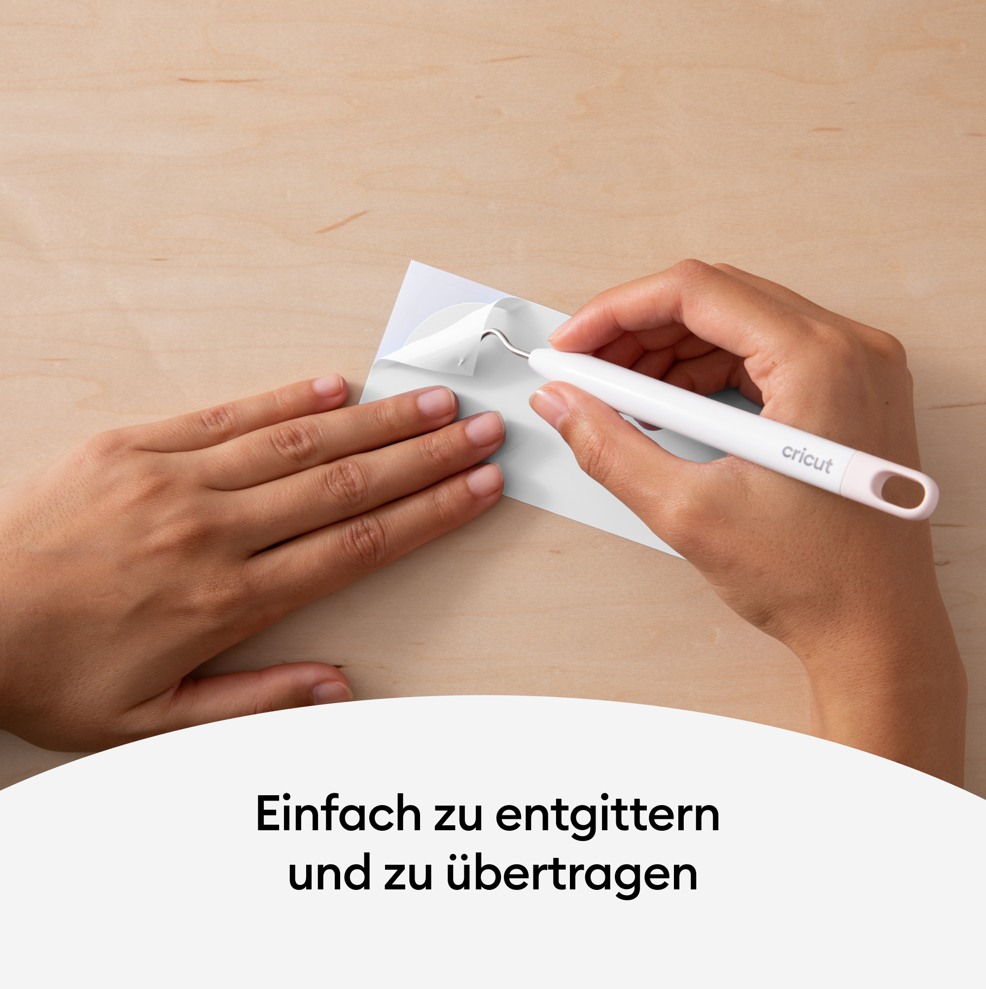 Zwei Hände, die ein weißes Papier von einem weißen Hintergrund mit einem weißen Cricut-Werkzeug abziehen.