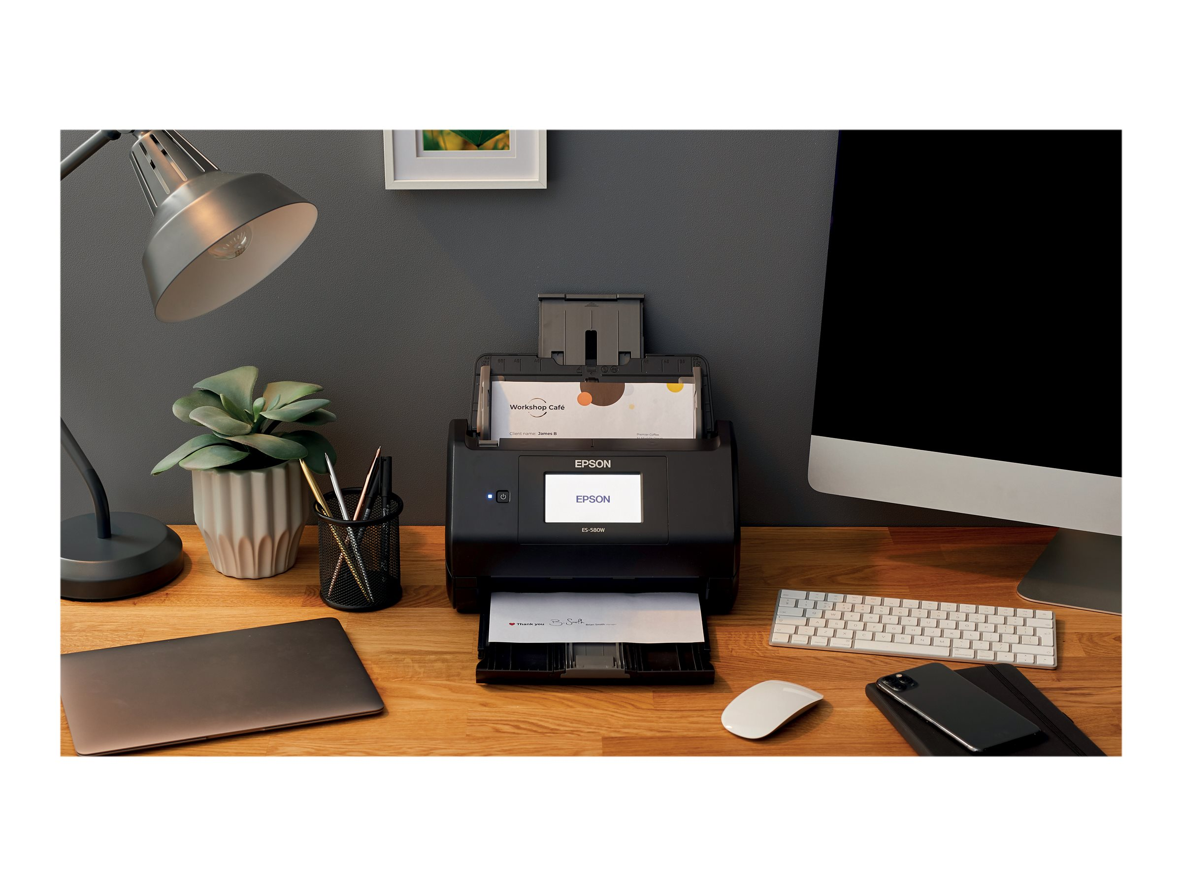 Schreibtischszene mit Scanner, Monitor, Tastatur, Maus und einer Topfpflanze.