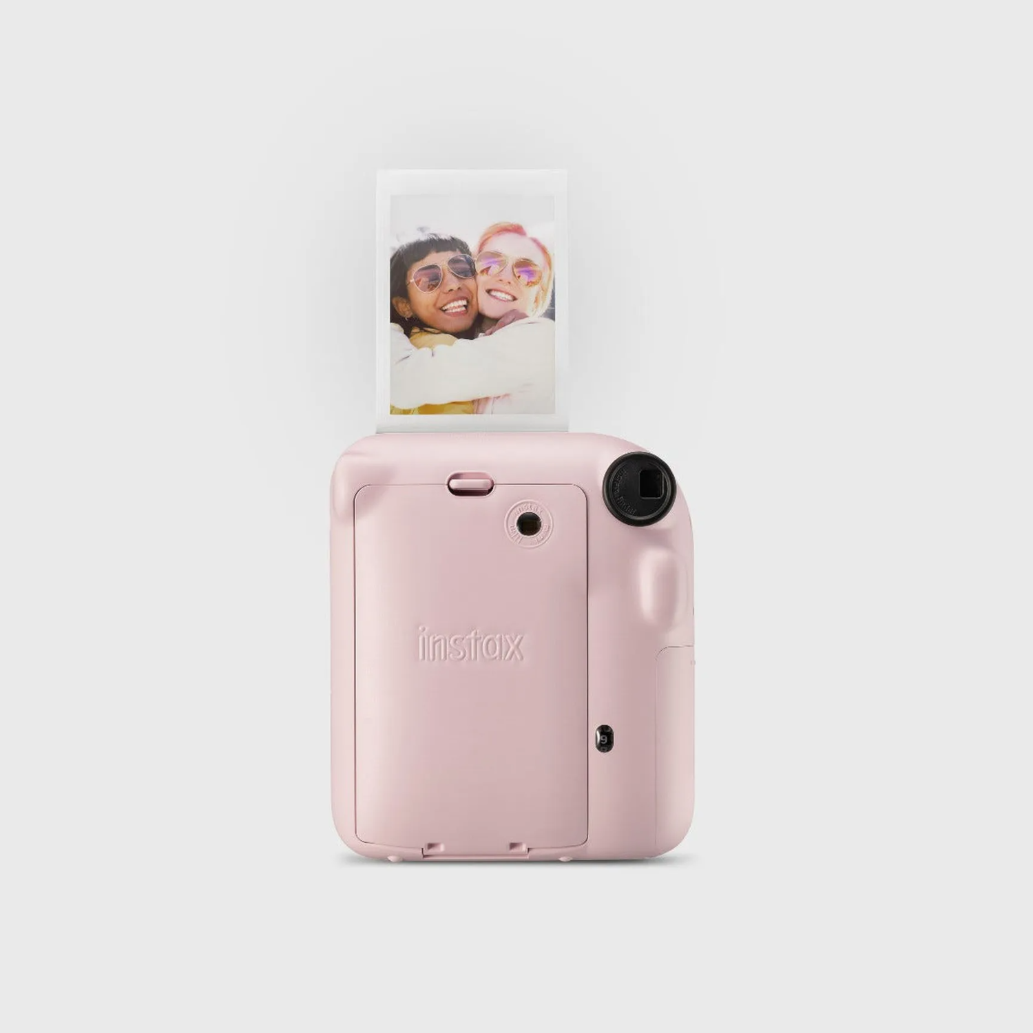 A pink instant camera with a photo being ejected, showing two smiling people.