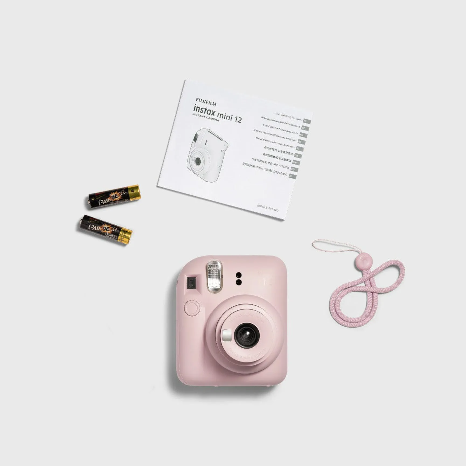 An Instax mini 12 camera with accessories on a white surface.