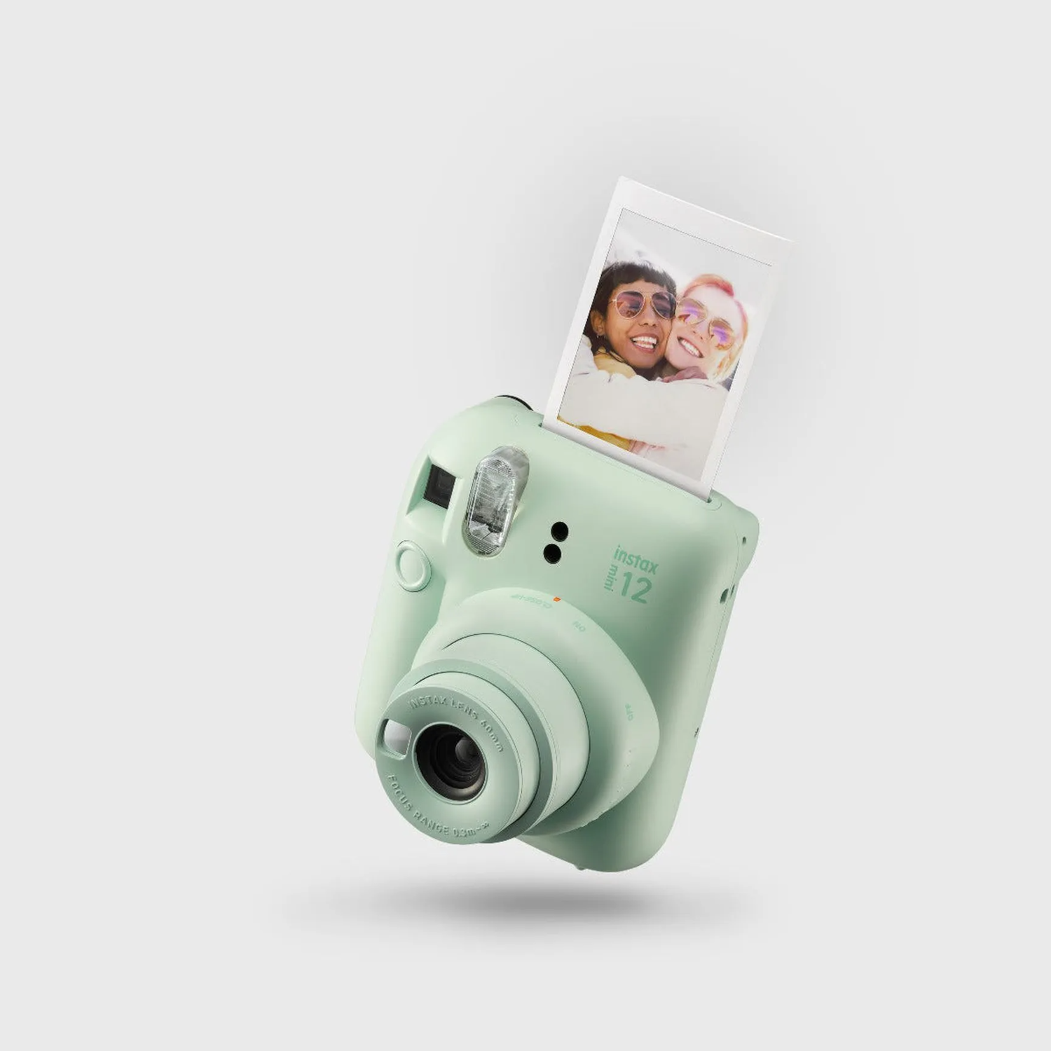 A light green instant camera with a photo of two smiling women.