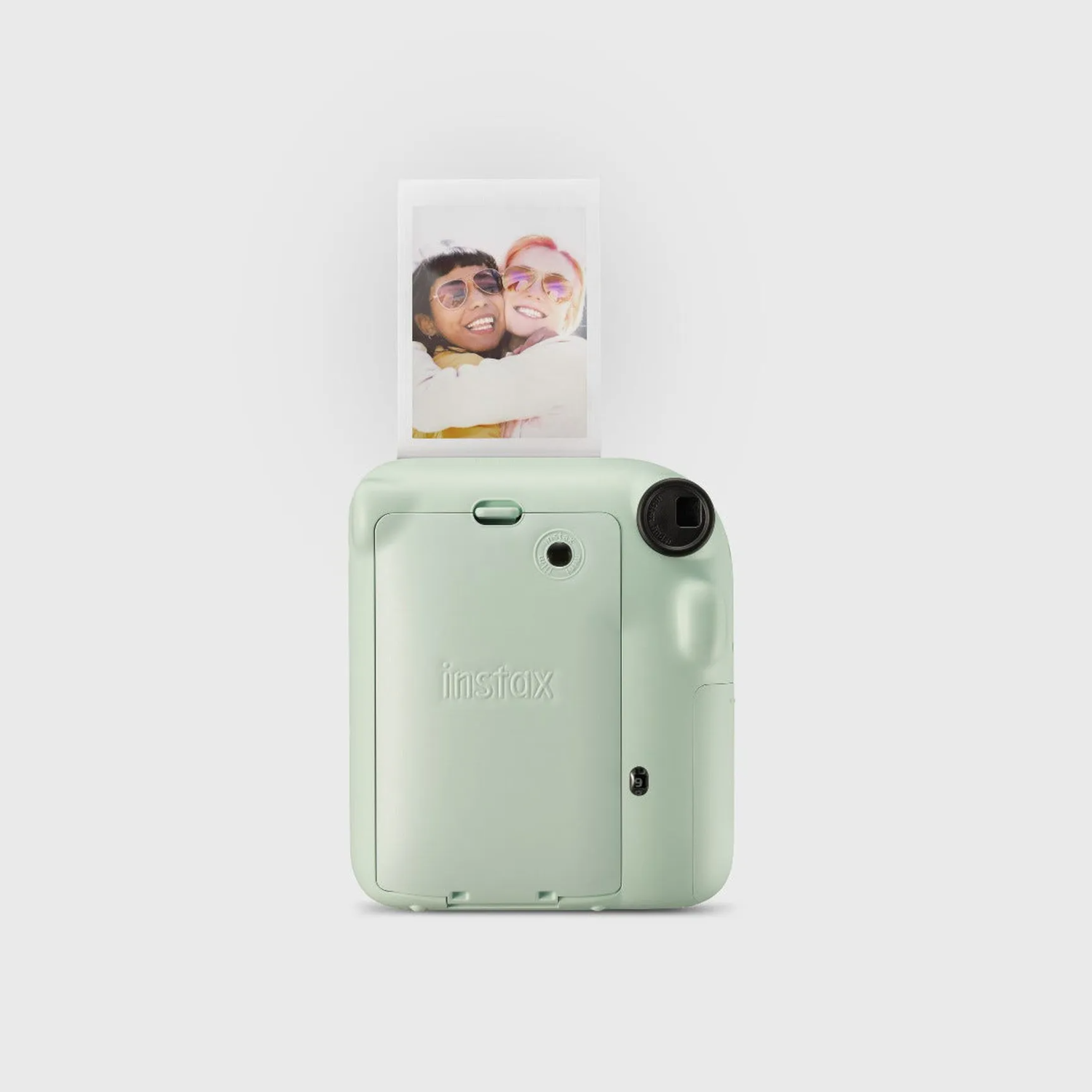 A mint green camera with a photo being ejected. Two people are in the photo.