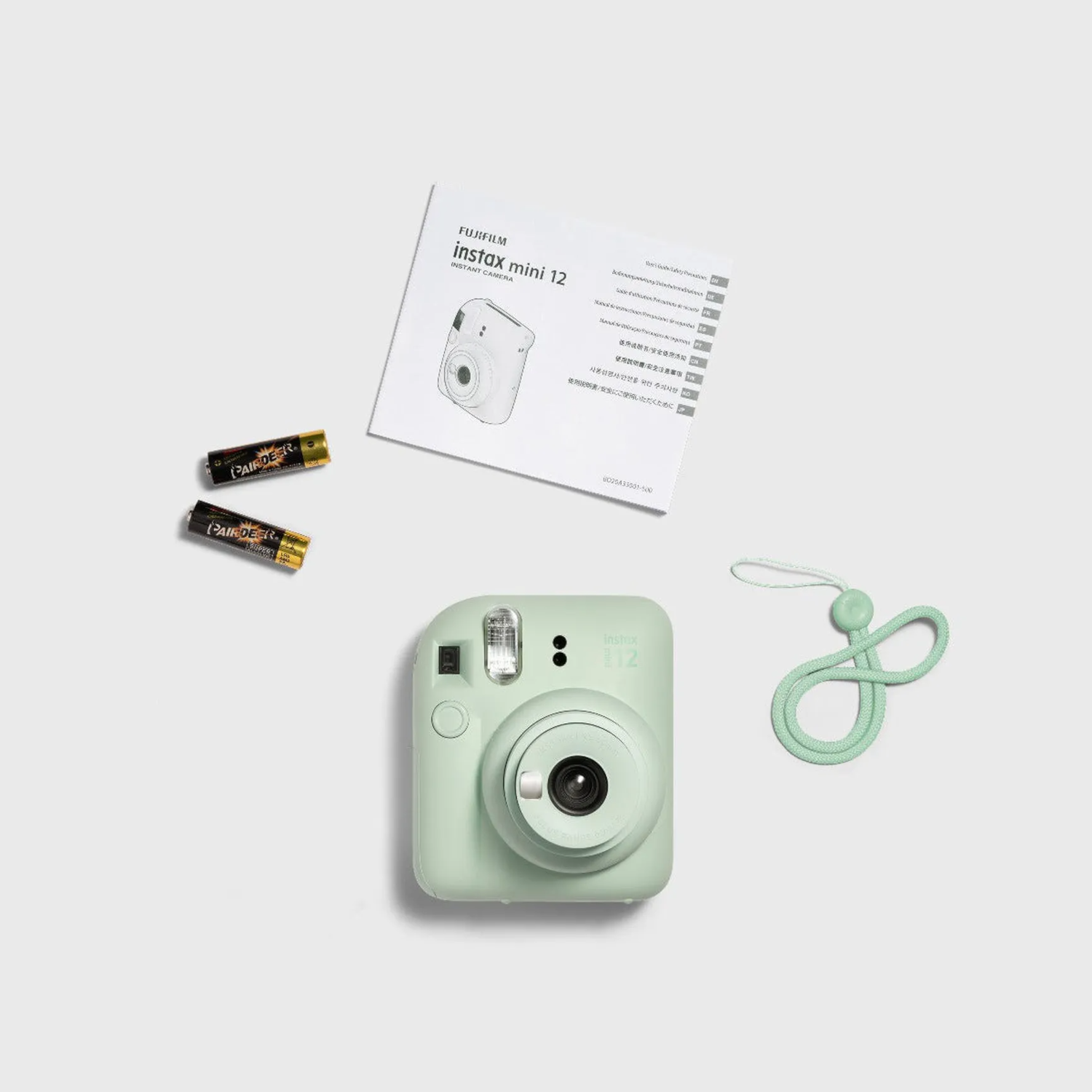 An instax mini 12 camera with accessories on a white surface.