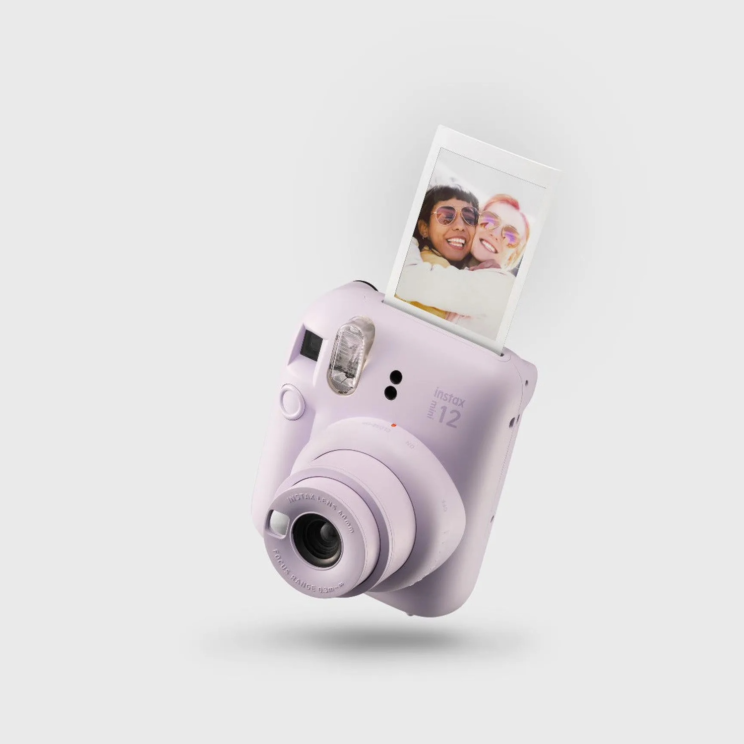 Un appareil photo Instax violet éjectant une photo, sur fond blanc.