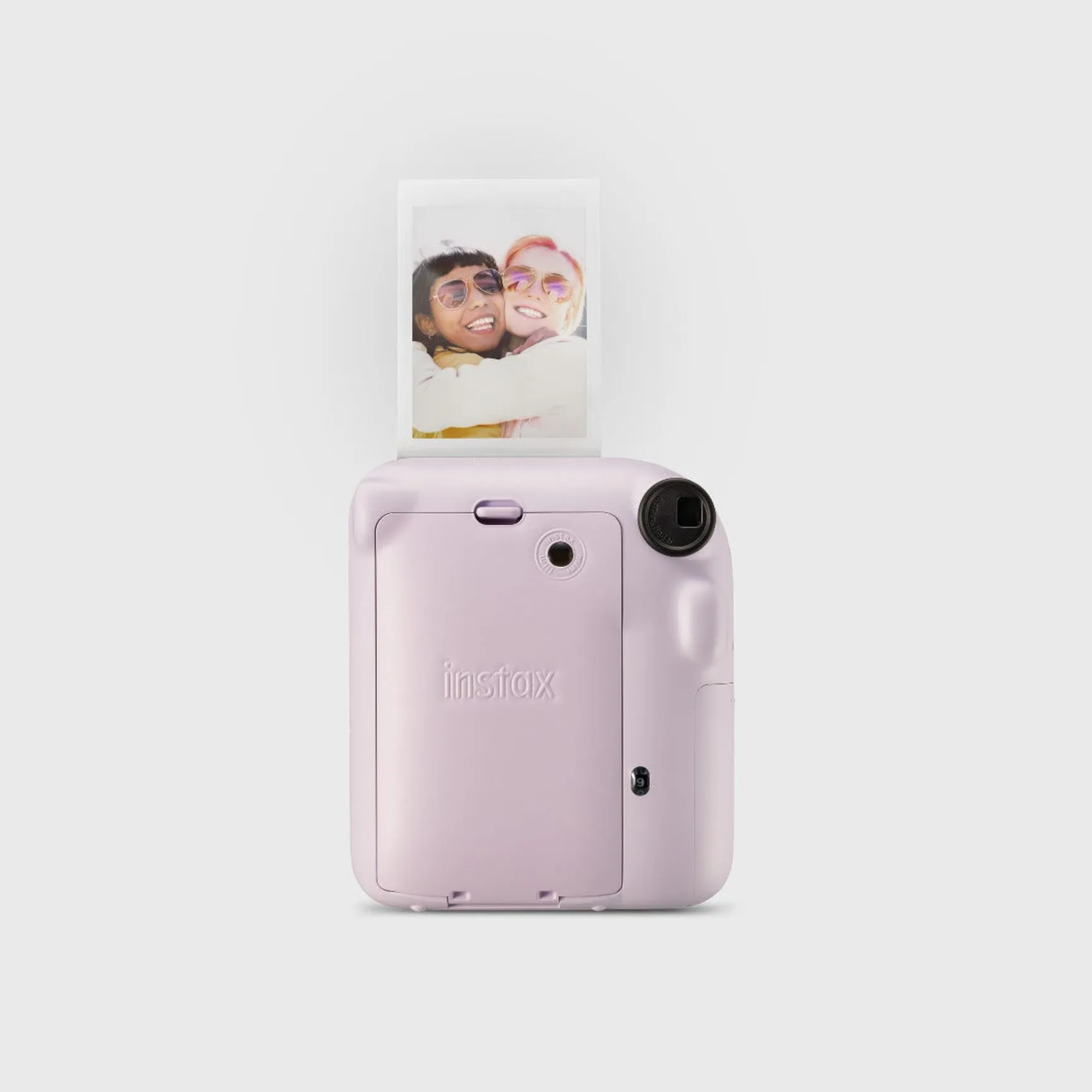Un appareil photo Instax rose avec une photo de deux femmes souriantes sortant du haut.