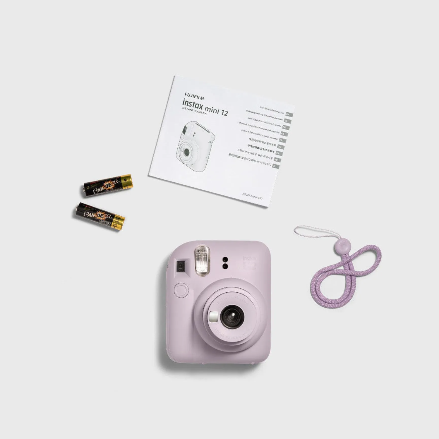 Un appareil photo Instax mini 12 violet, des piles, un manuel et une sangle sur une surface blanche.
