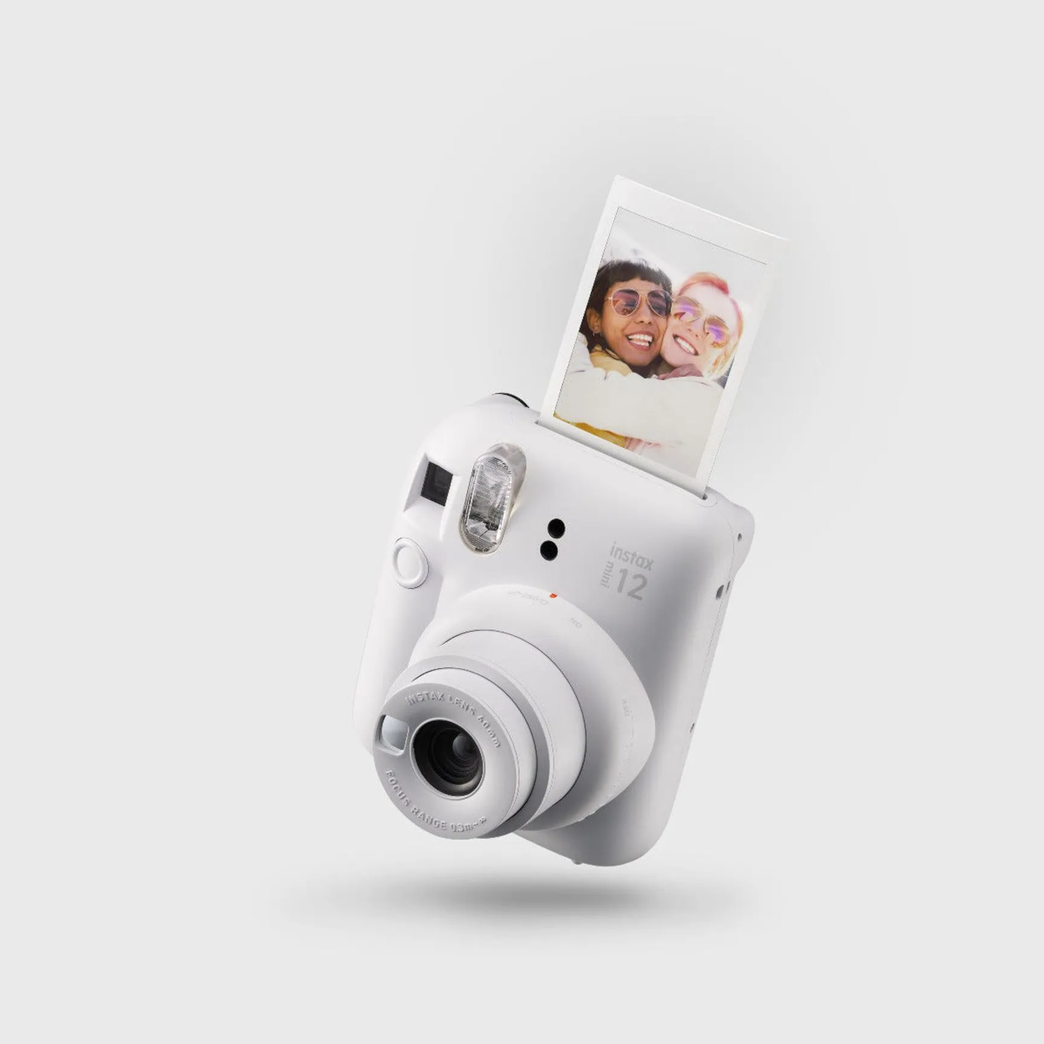 White Instax camera with a printed photo of two people.