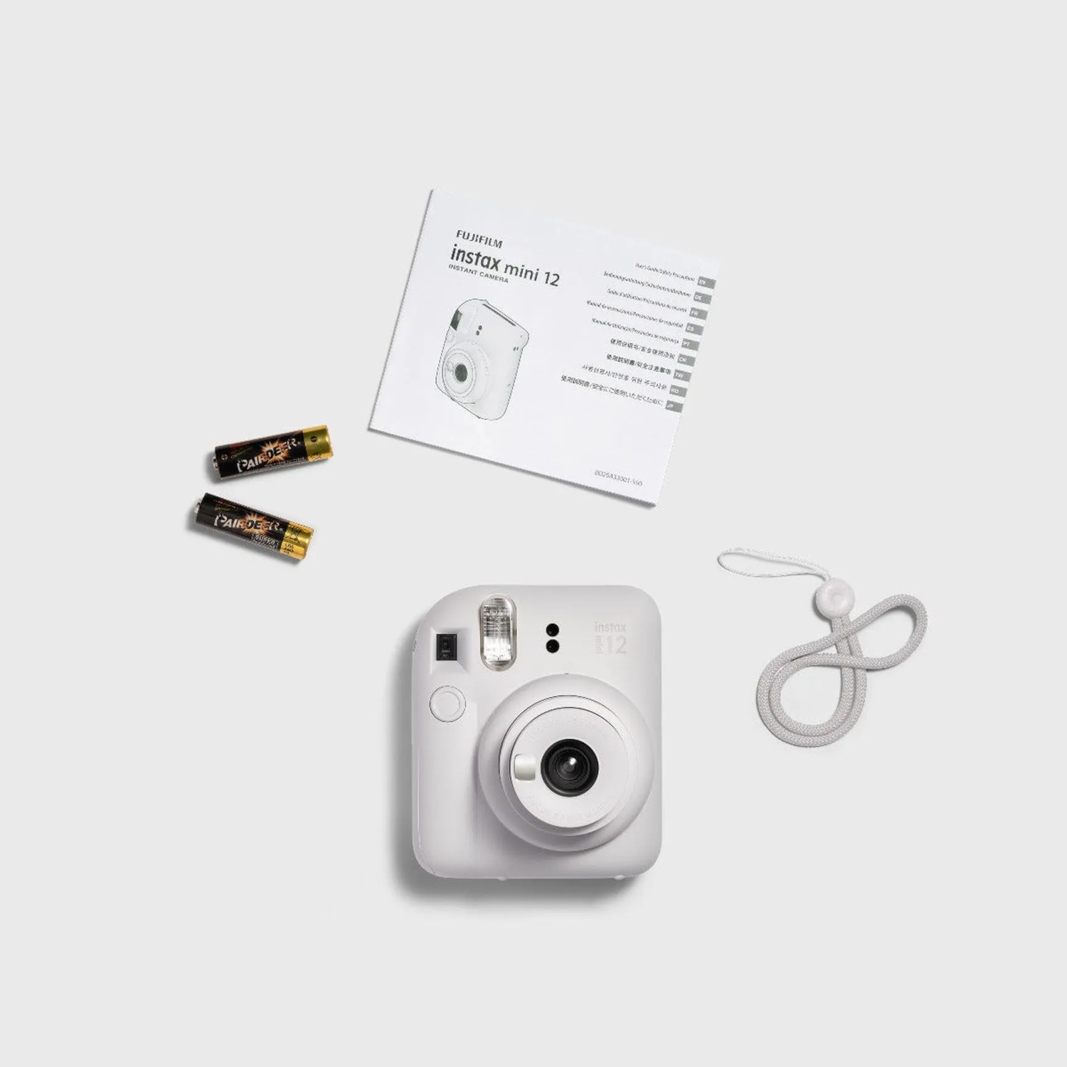 An instant camera, batteries, and instructions are on a white surface.