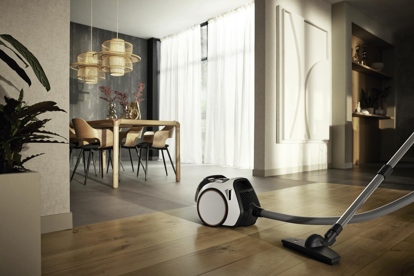 Staubsauger auf Holzboden in modernem Esszimmer. Tisch, Stühle und Leuchten sind sichtbar.