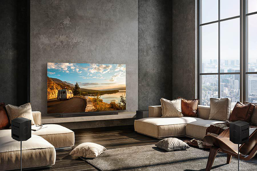 Wohnzimmer mit großem Fernseher, Sofa, Lautsprechern und Fenster mit Stadtblick.