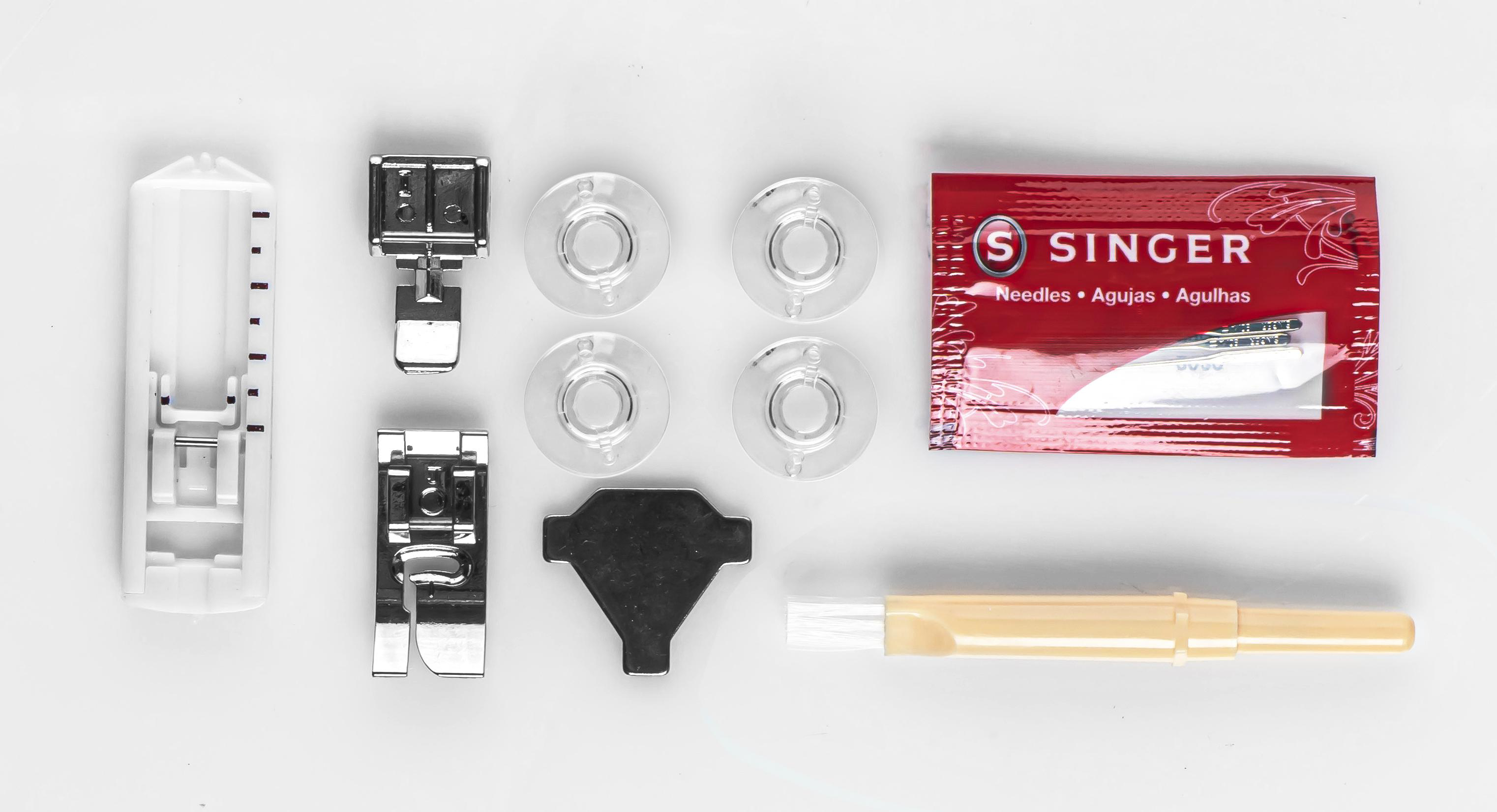 Nähmaschinenzubehör: ein Fuß, Spulen, Nadeln und eine rote Packung Singer-Nadeln auf weißem Untergrund.