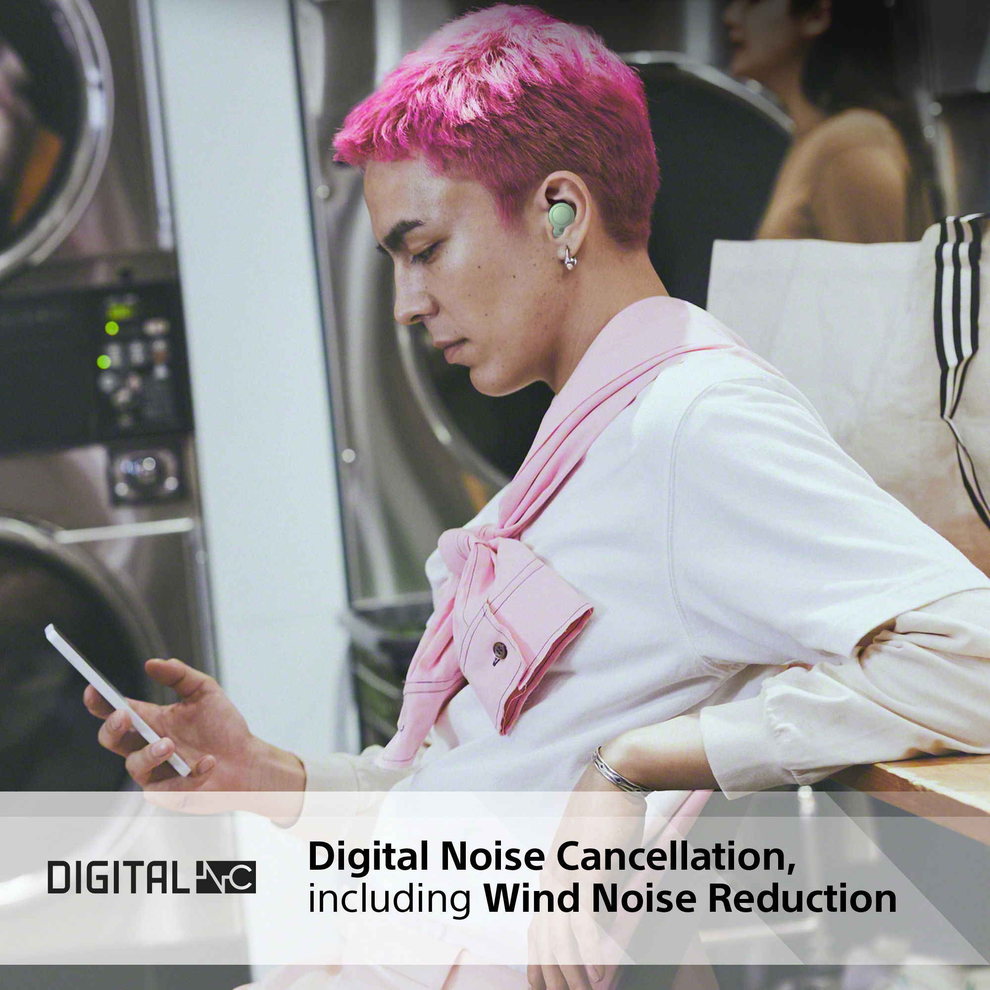 Ein Mann mit pinkfarbenen Haaren benutzt ein Tablet, trägt Ohrhörer. Text: Digital Noise Cancellation.