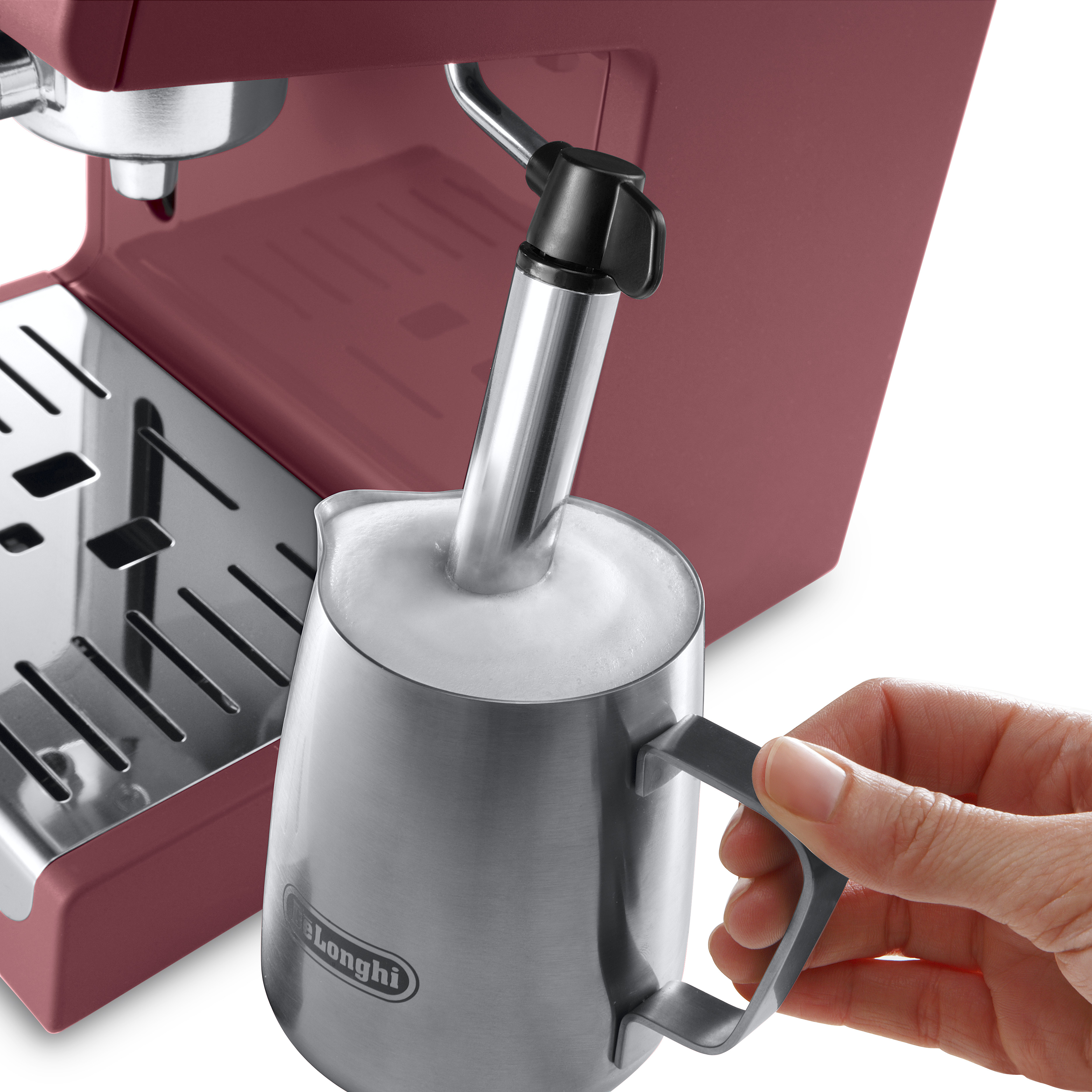 Máquina de espresso. Mano vertiendo leche en jarra de metal. Se hace espuma.