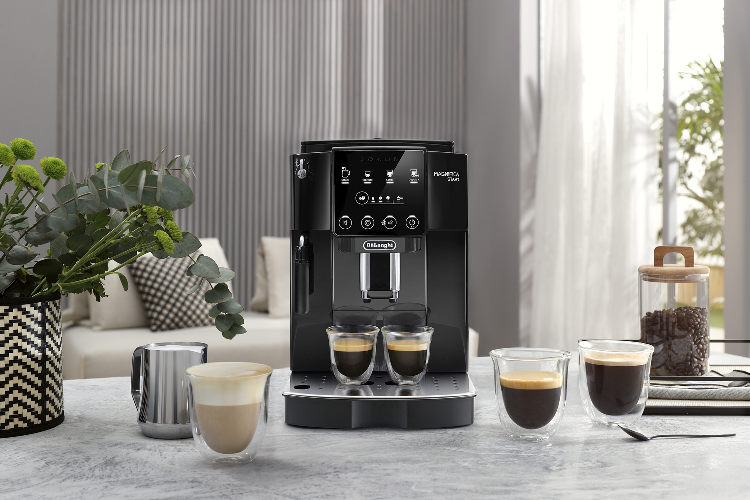 Cafetera espresso negra, con dos vasos de café y algunos granos de café.
