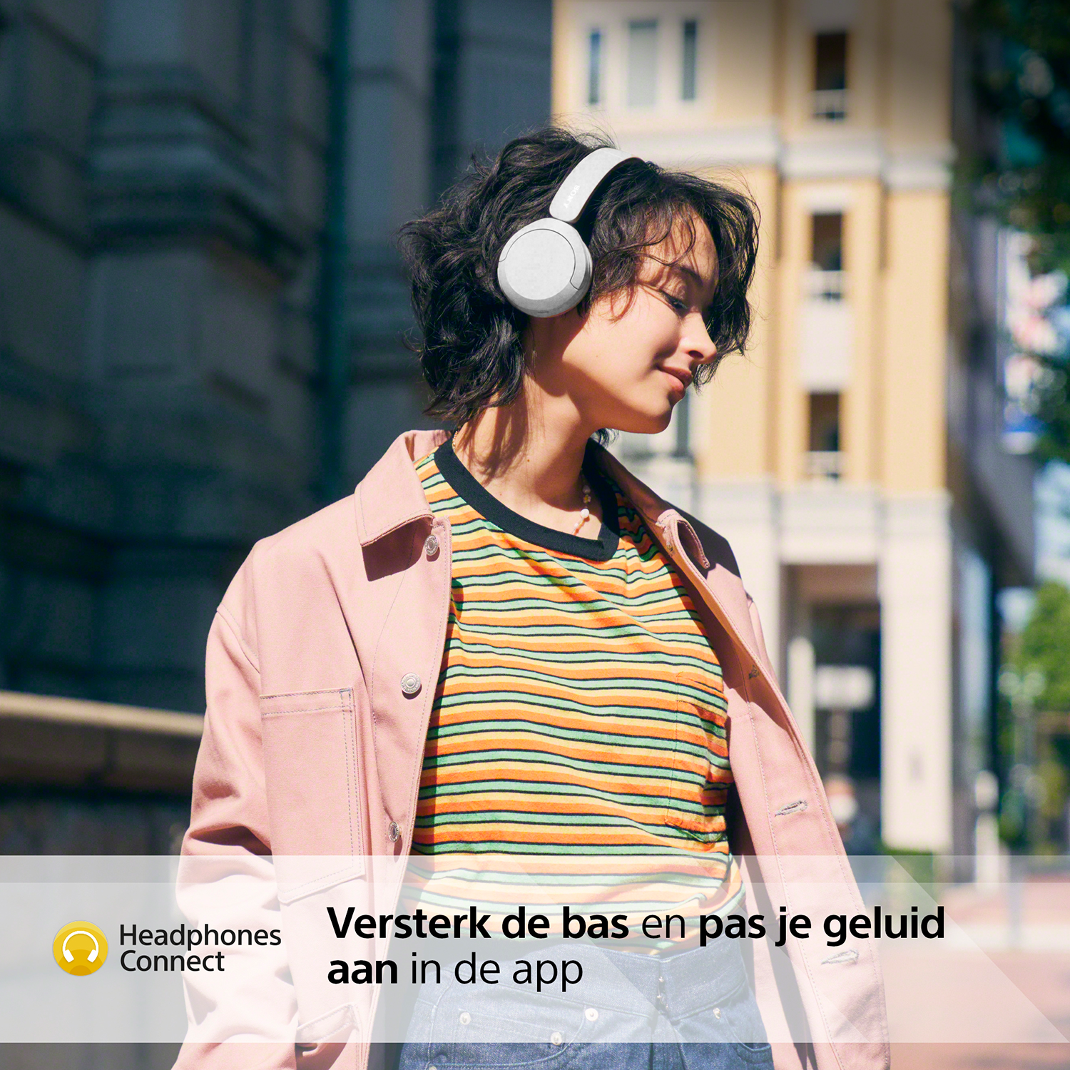 Een vrouw met een koptelefoon voor een gebouw met Nederlandse tekst over geluid.