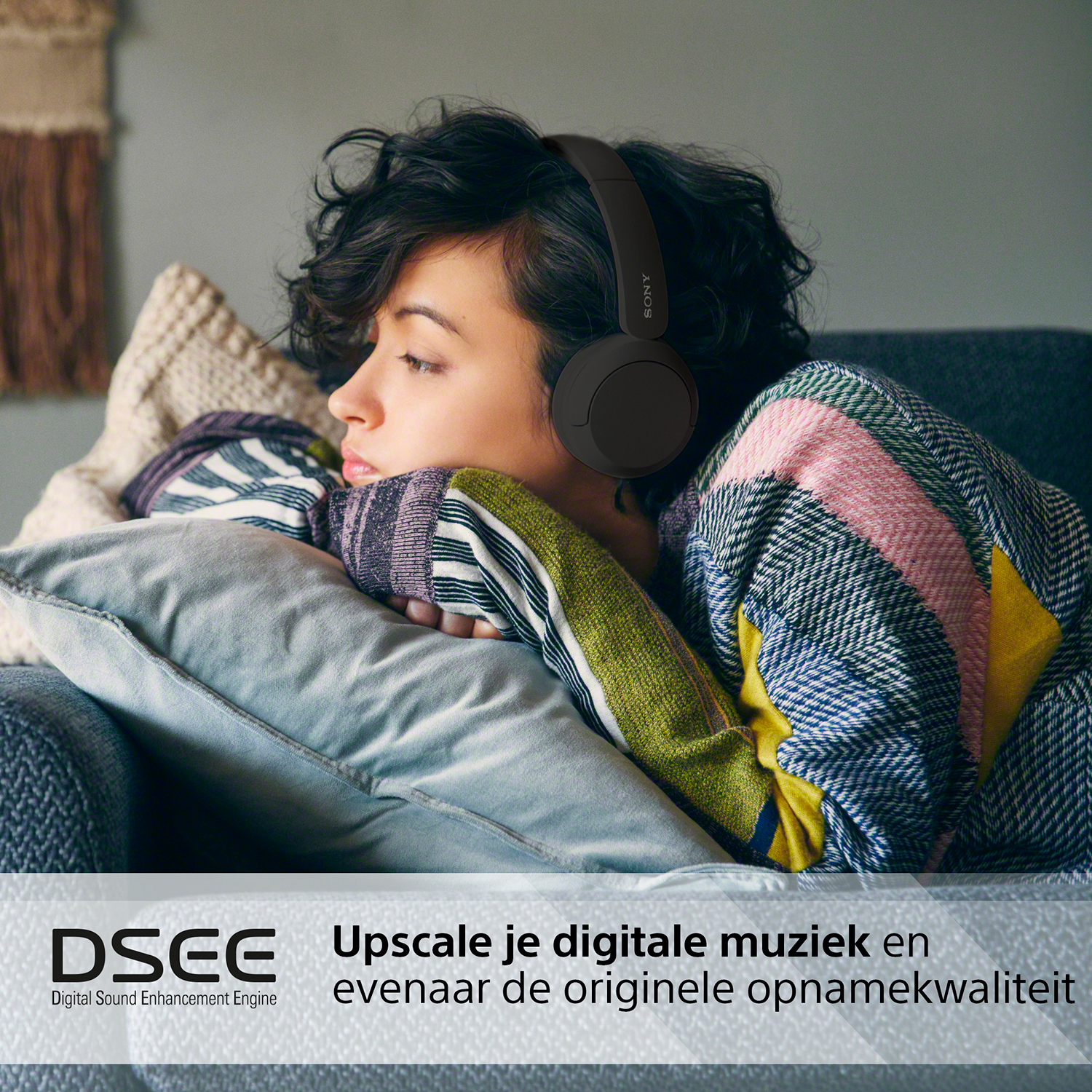 Vrouw die op een bank ligt en een koptelefoon draagt.
