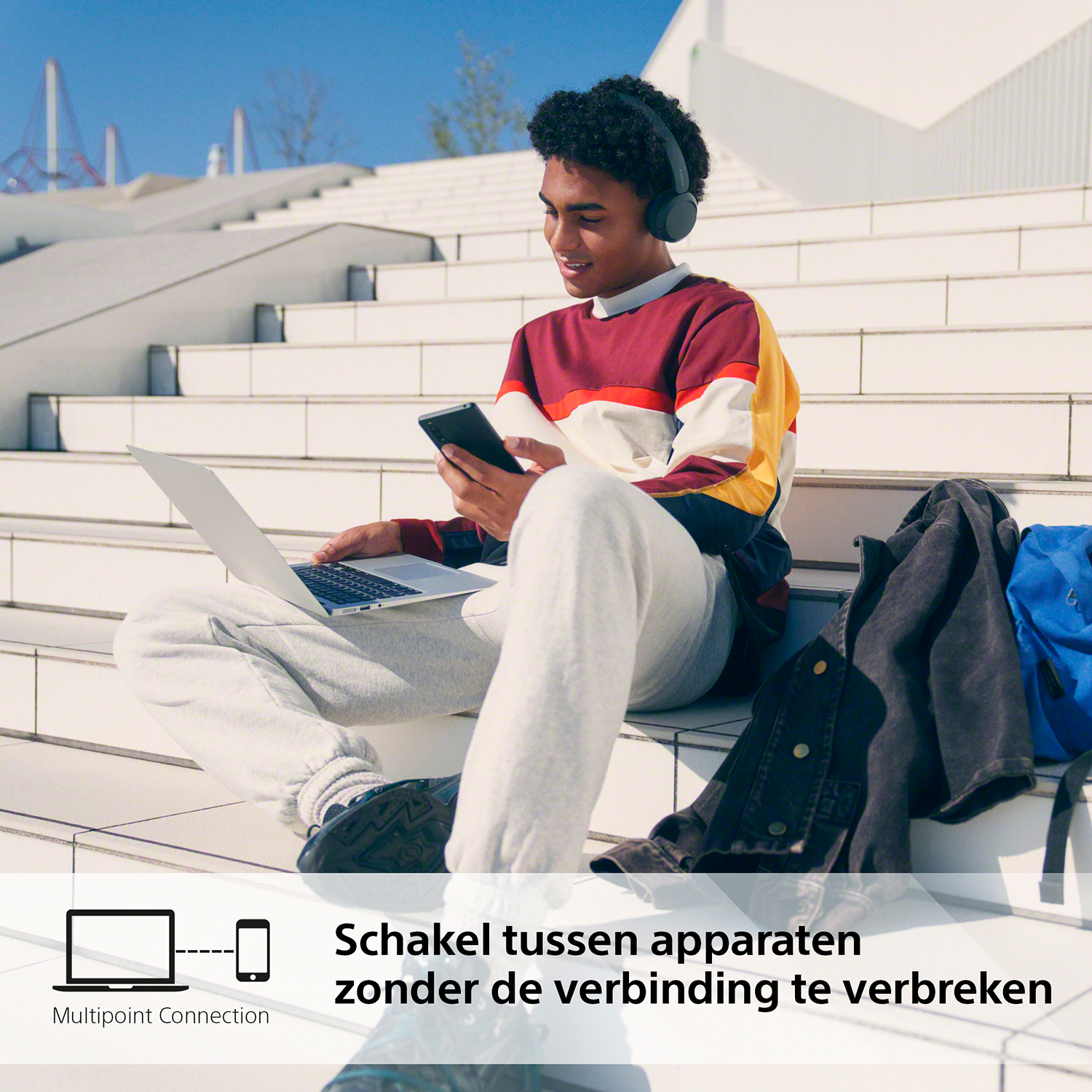 Een jonge man met koptelefoon en laptop, die een telefoon gebruikt. Tekst: 'Wissel tussen apparaten'.