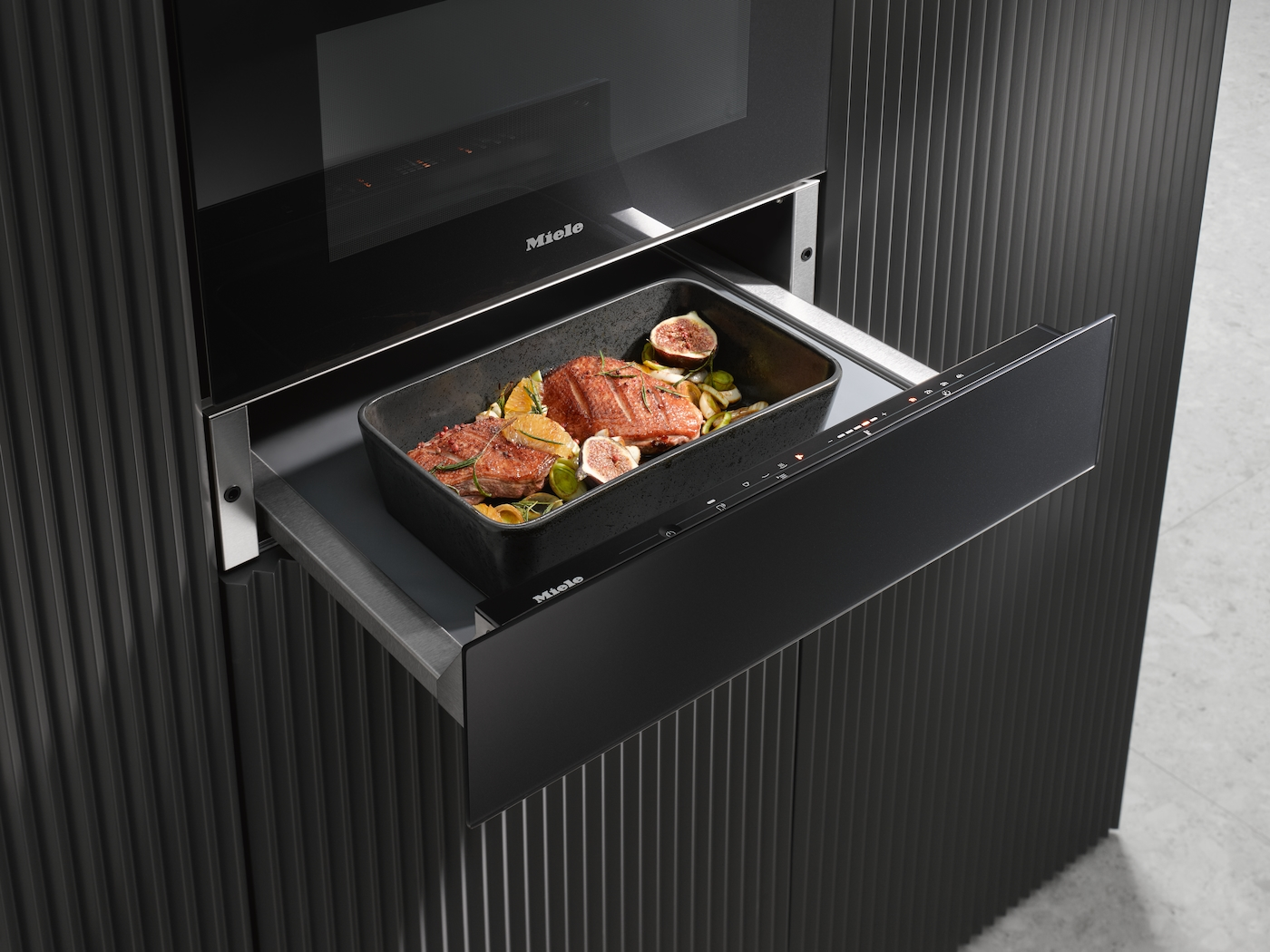 Eine Miele Wärmeschublade enthält eine Bratreine mit Lachs, Feigen, Orangen und Rosmarin.