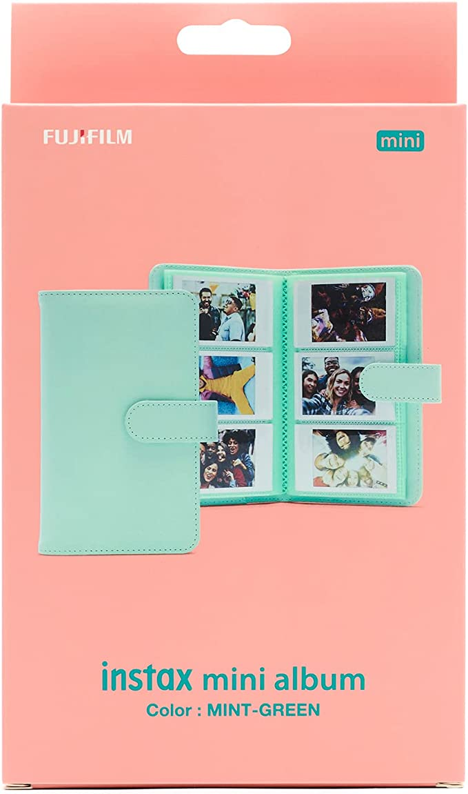 Un álbum Instax mini verde menta en una caja con fotos dentro.