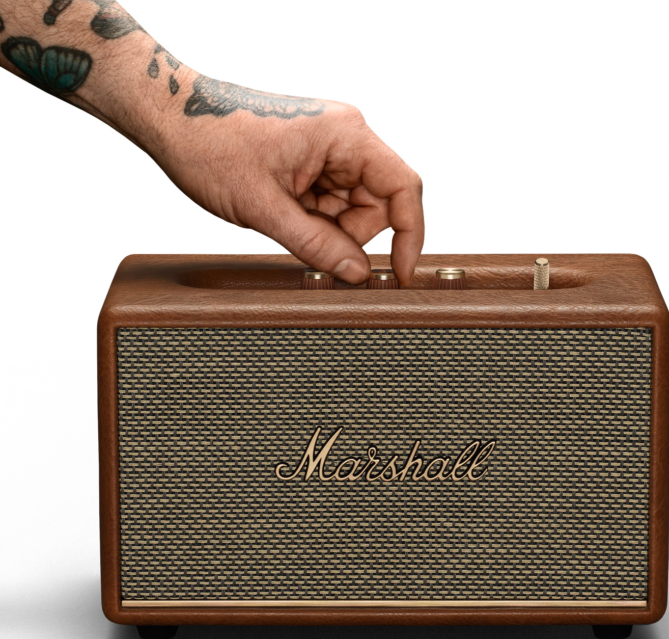 Main ajustant les boutons d'un amplificateur Marshall marron; tatouage sur le bras.