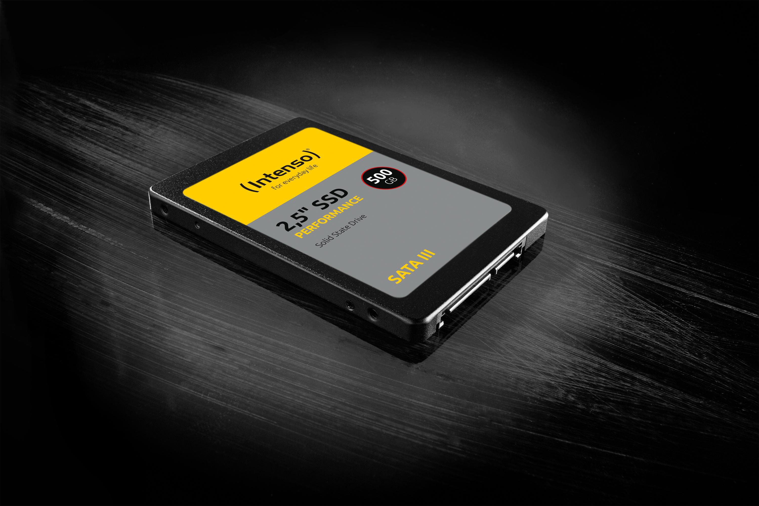 Schwarze SSD mit weißem und gelbem Etikett, platziert auf glänzender schwarzer Oberfläche.
