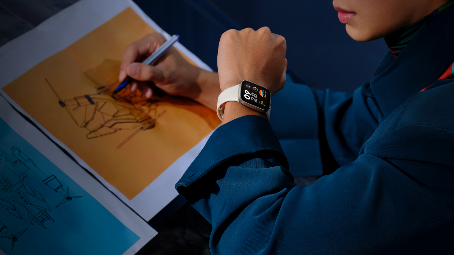 Persona usando un reloj inteligente, dibujando en papel. Chaqueta azul, piel clara y reloj con correa crema.