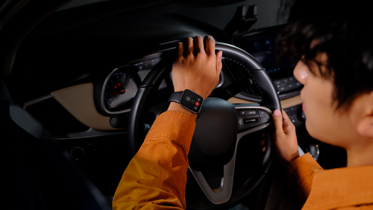 Persona en un coche con reloj inteligente, sosteniendo un volante. Interior oscuro.