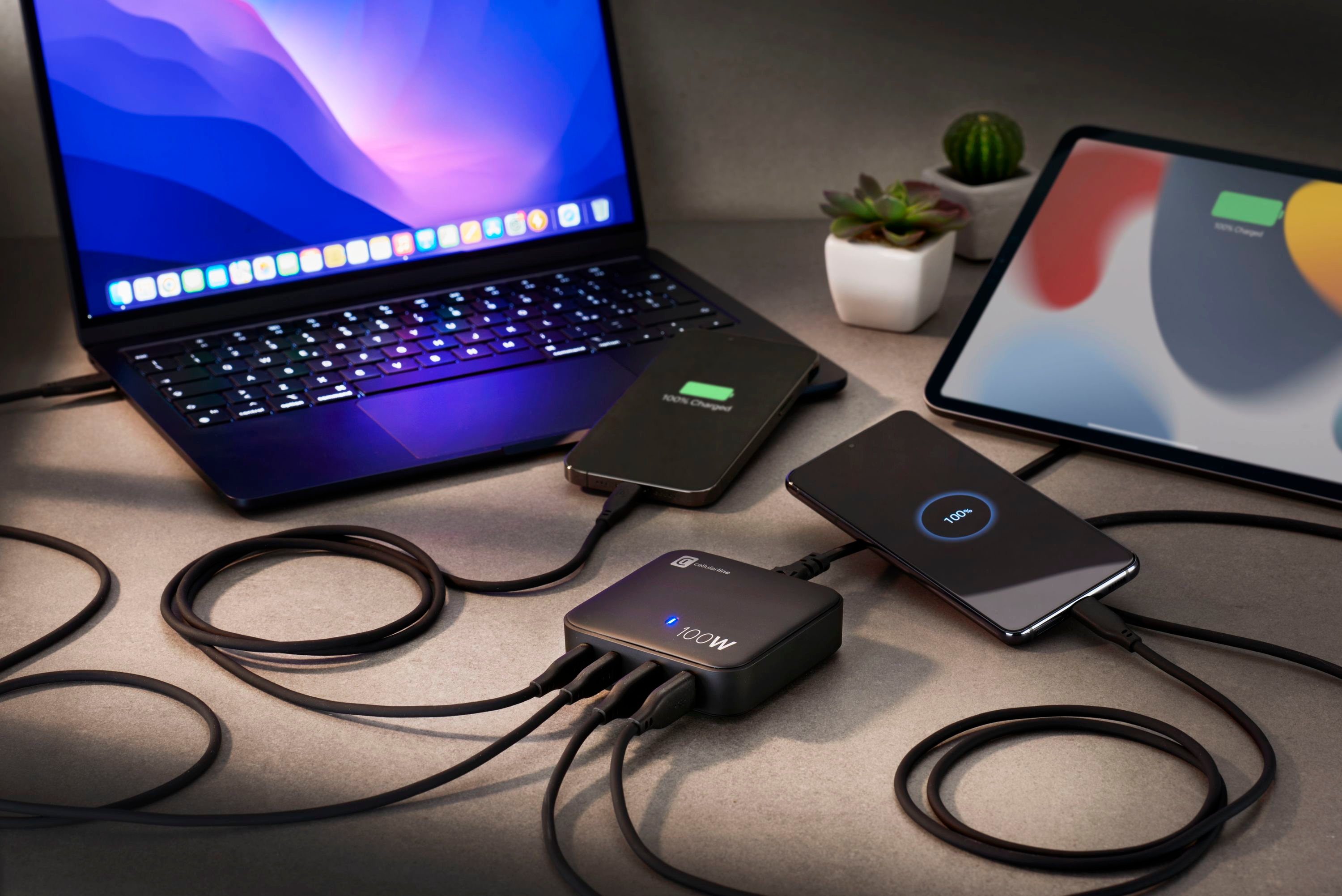 Laptop, Telefon und Tablet, die von einem schwarzen Multiport-Ladegerät geladen werden.
