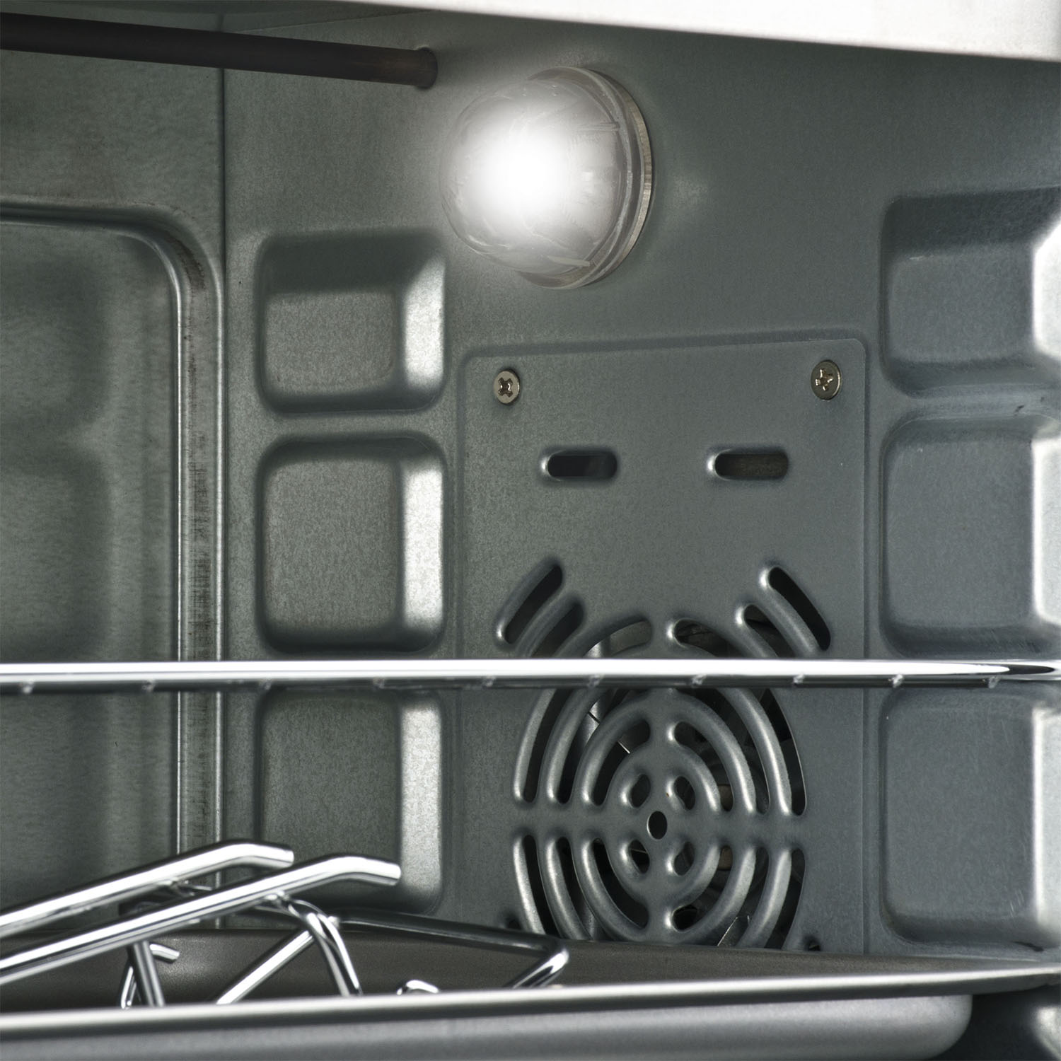 Interno di un forno, luce accesa, griglia ed elemento riscaldante visibili. Superfici metalliche, interno grigio.