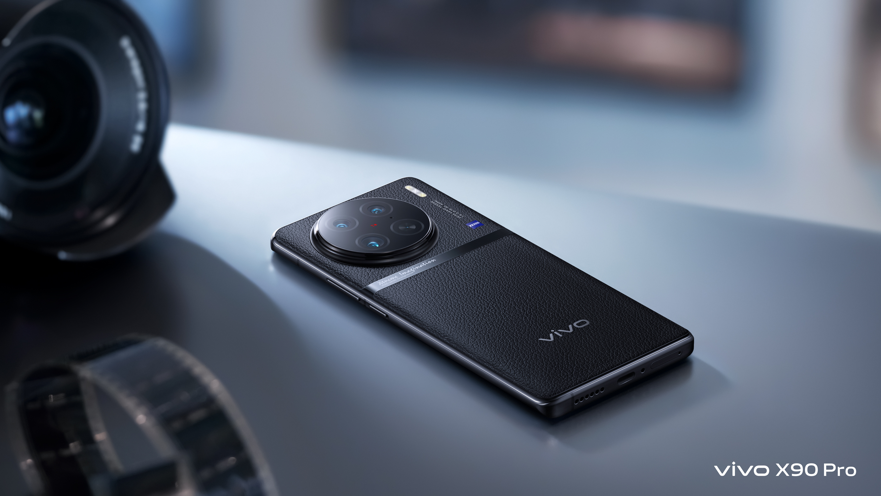 Schwarzes Smartphone mit mehreren Kameras, Objektiv und Filmrolle im Hintergrund.
