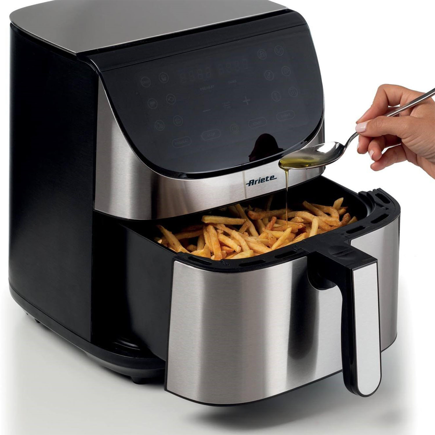 Una friggitrice ad aria con patatine fritte e olio aggiunto con un cucchiaio.