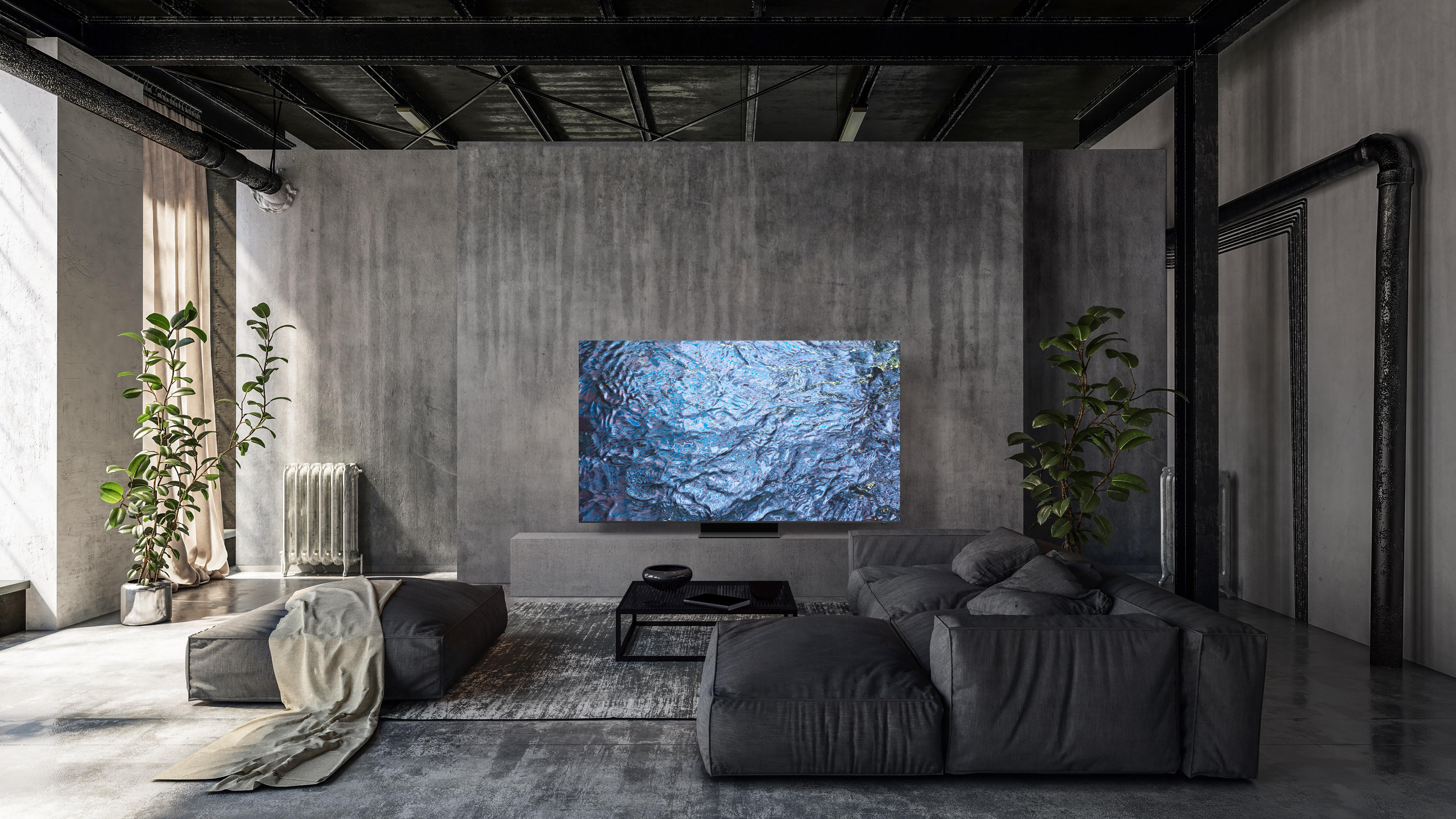 Modernes Wohnzimmer mit grauer Couch, Pflanzen, großem Fernseher an Betonwand, Dekoelementen.