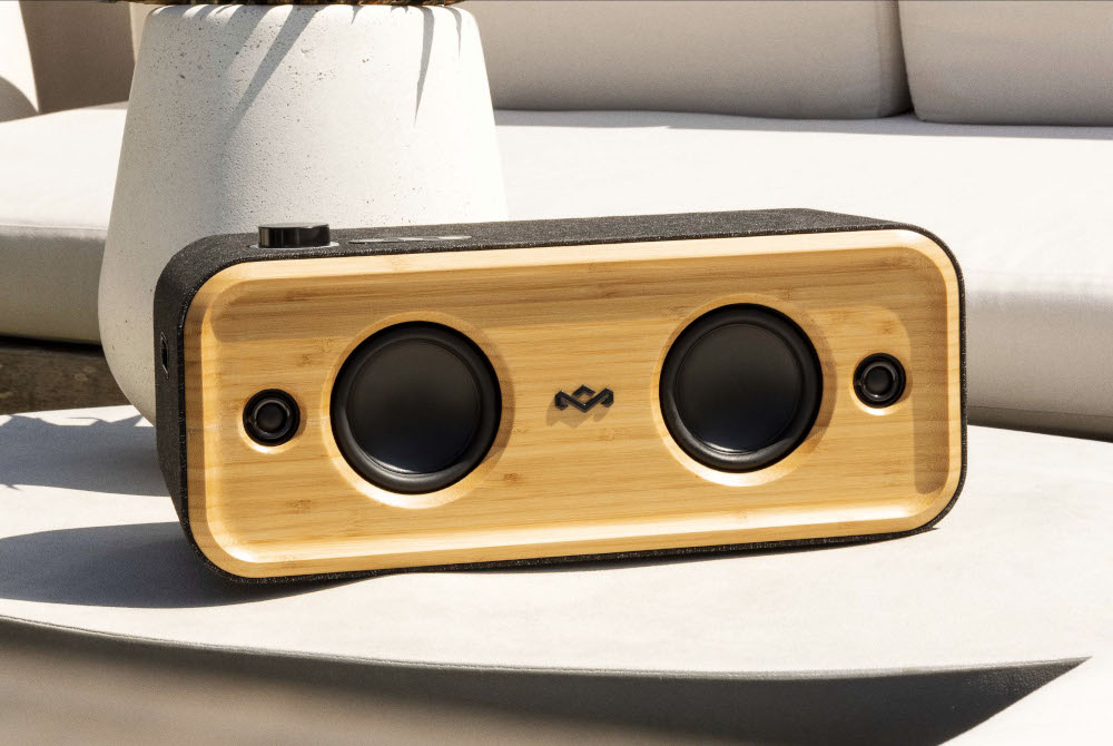 Wooden speaker with two round speaker grills. Black fabric on top and sides. White background.