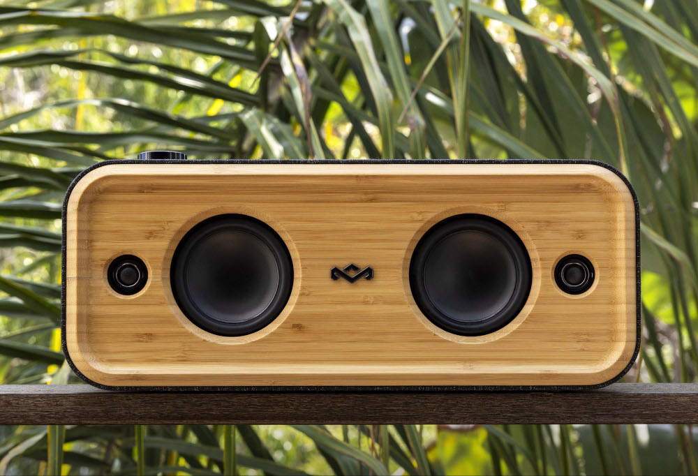 Bamboo speaker with two speakers and a black control knob. Set on wood.