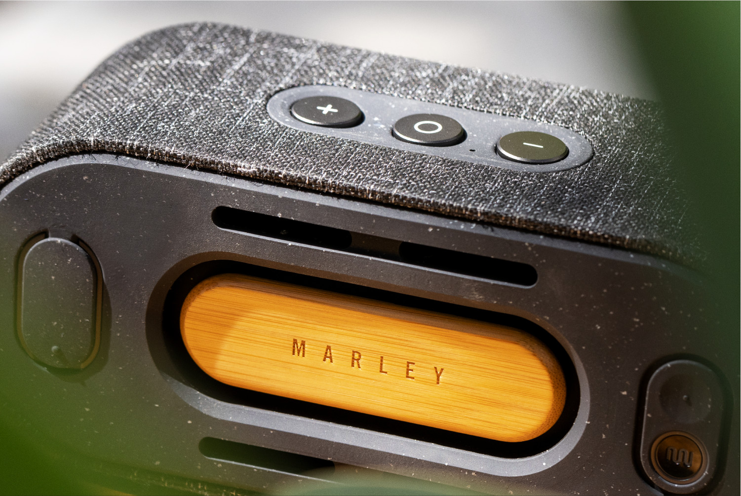Een close-up van een zwarte luidspreker met knoppen en het woord MARLEY in hout. De achtergrond is wazig.