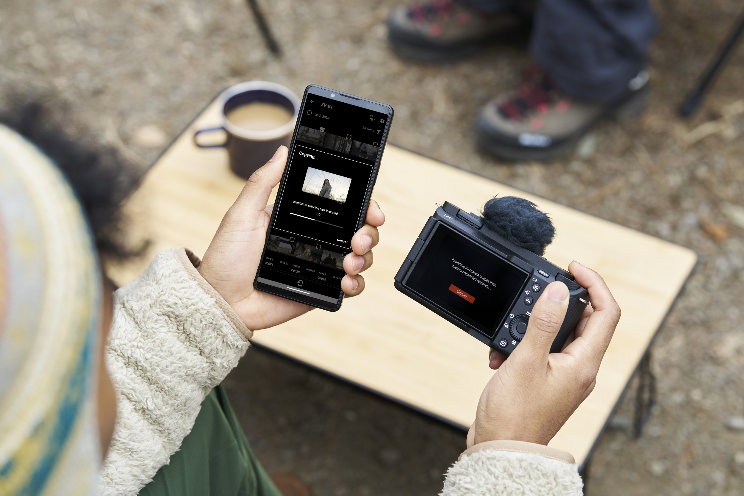 Eine Person hält ein Telefon und eine Kamera, beide zeigen eine Videoschnittstelle.