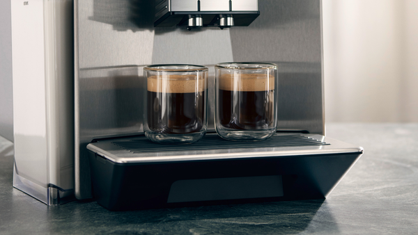 Gri mermer yüzey üzerinde, kahve dolu iki cam bardaklı espresso makinesi.