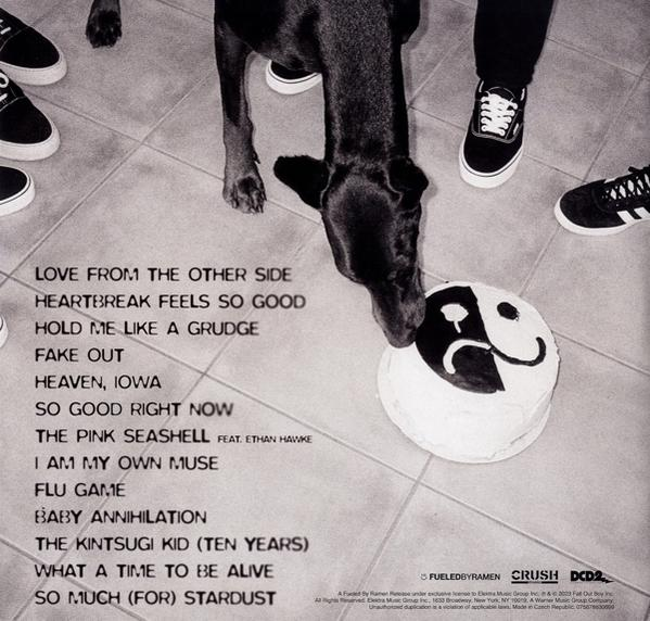 Albumcover mit Songtiteln und einem Hund auf einem Kuchen mit traurigem Gesicht, umgeben von Schuhen.