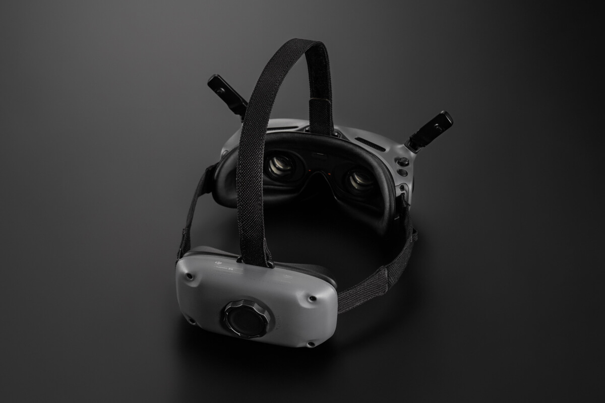 Casque VR sur une surface sombre. Gris et noir avec une sangle. Les lentilles sont visibles.