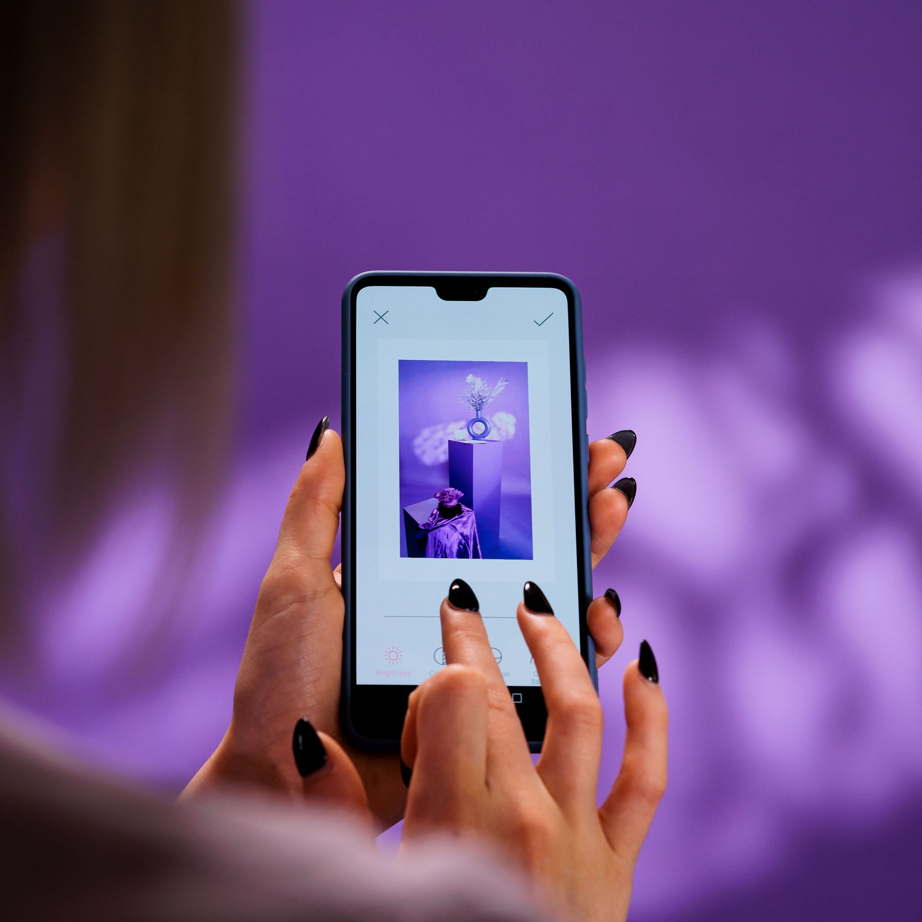 Mani di una persona che tiene un telefono con una foto sullo schermo, sfondo viola.