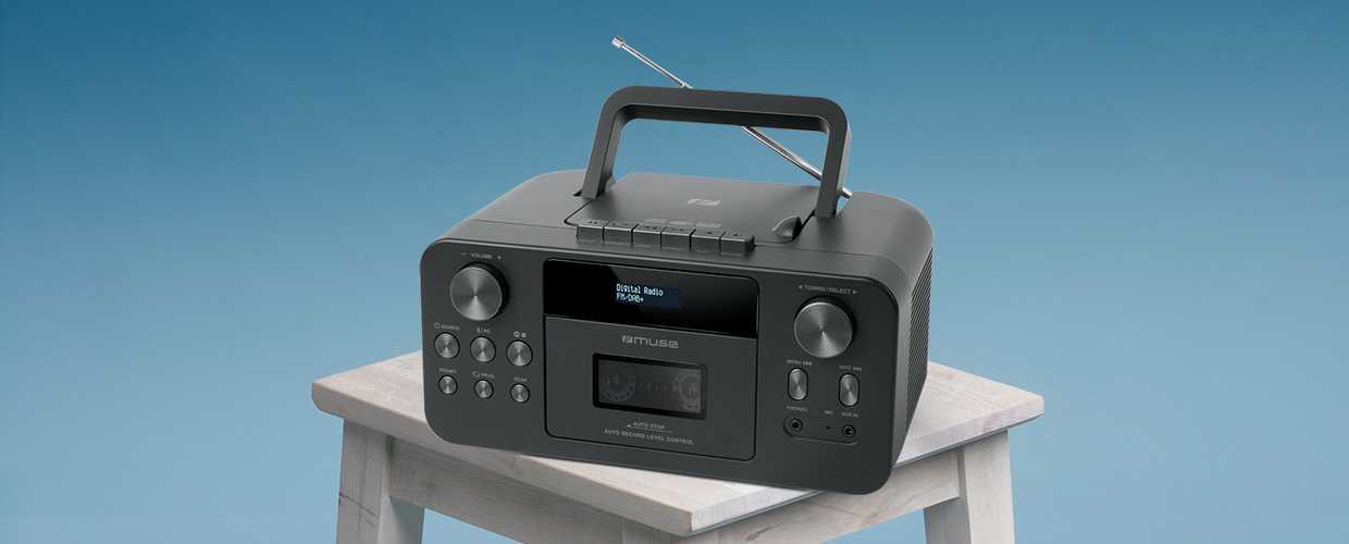 Una radio nera su uno sgabello bianco su sfondo blu. Ha una maniglia e dei pulsanti.