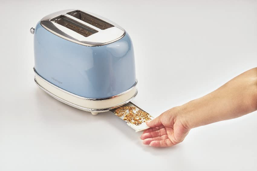 Ein blau-weißer Toaster mit Krümeln im Fach. Eine Hand zieht das Fach heraus.