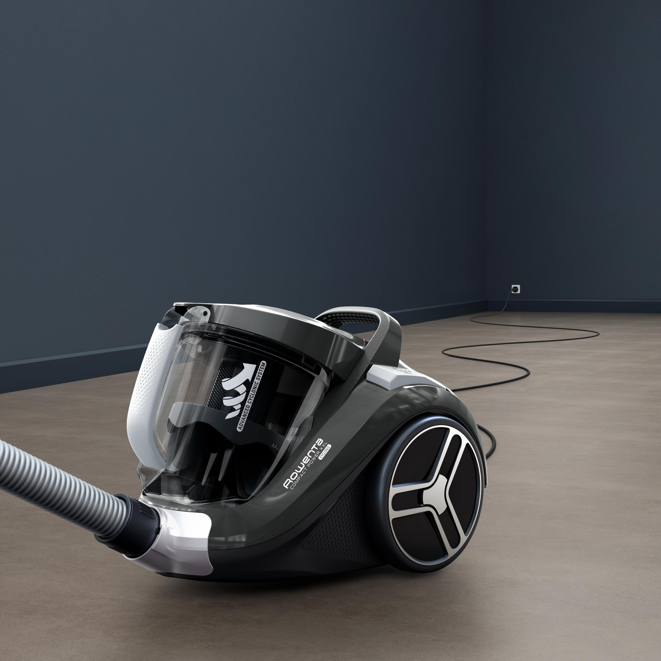 Schwarz-grauer Staubsauger, der Schlauch ist befestigt, auf braunem Boden mit dunkelblauer Wand.