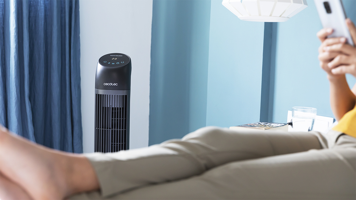Persona relajándose con los pies en alto, ventilador y teléfono.