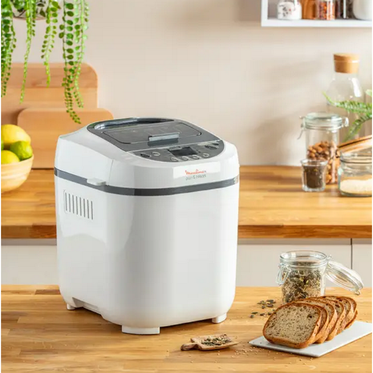 Witte broodbakmachine op een houten aanrecht, met brood en ingrediënten.