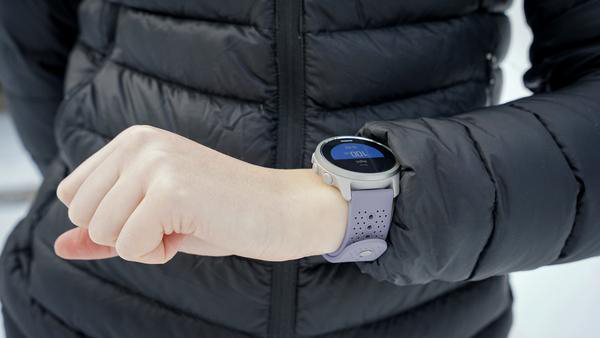 Person trägt eine schwarze Jacke und eine Uhr mit lila Armband.