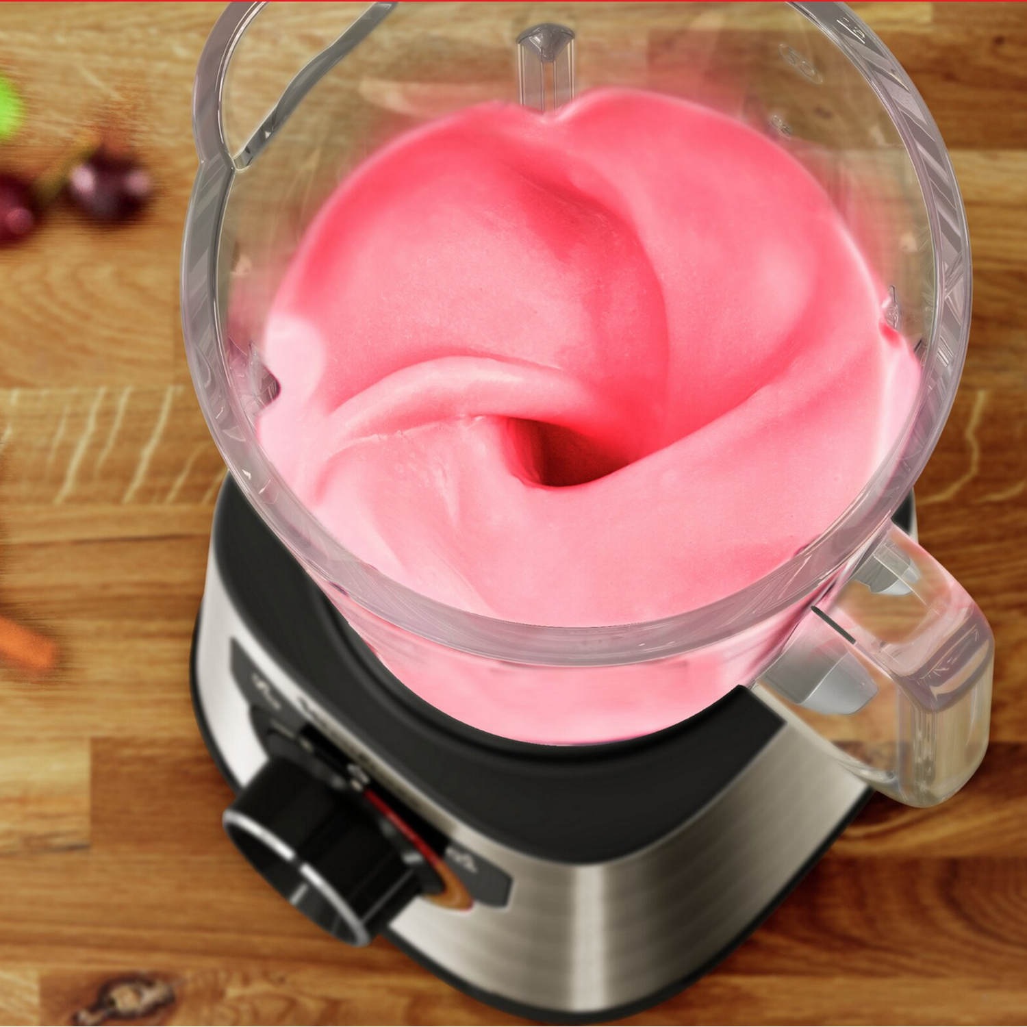 A blender with pink mixture inside, in a kitchen setting. The blender is on a counter.
